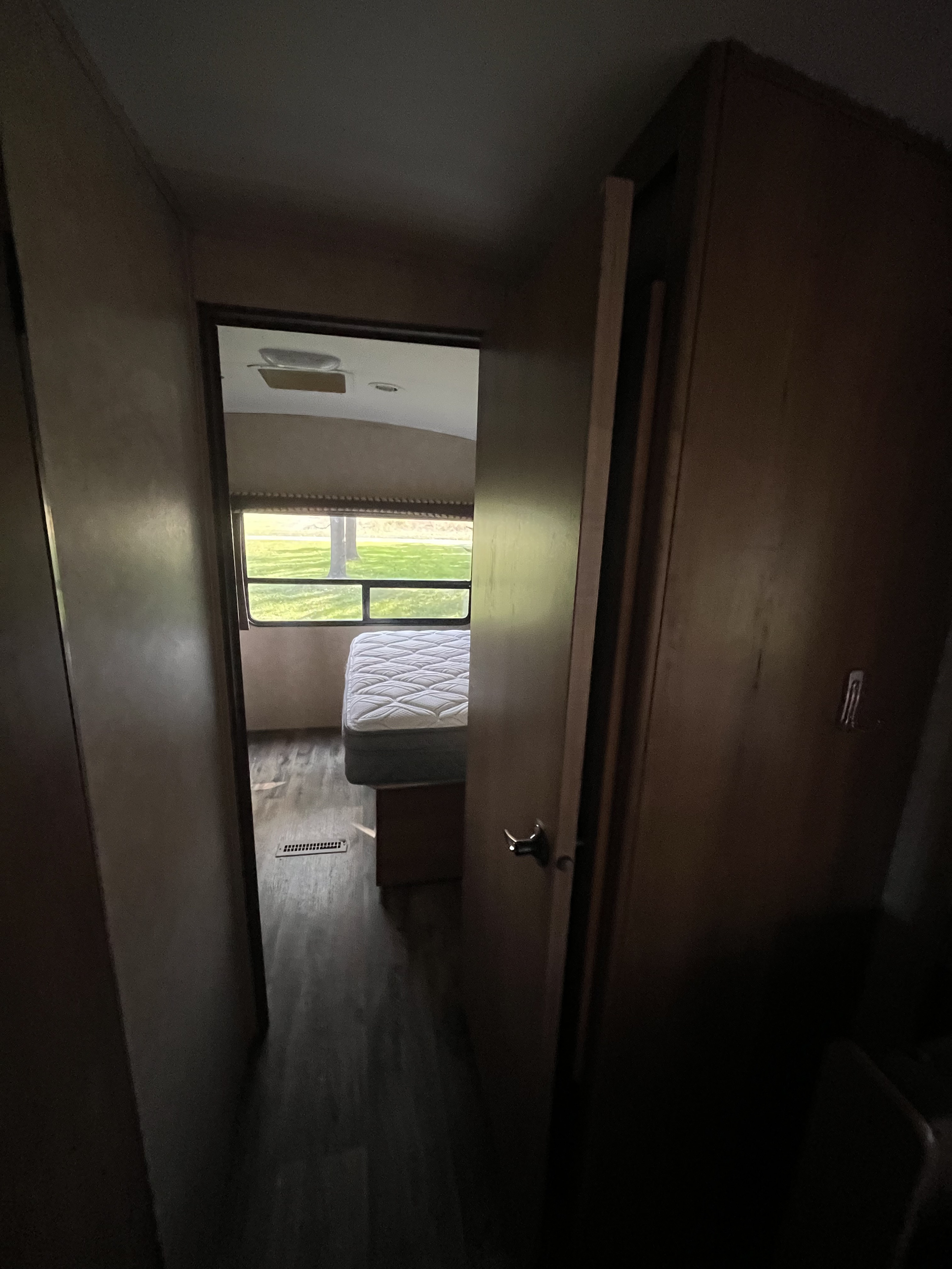 Cozy RV rental interior: hallway leading to a bright bedroom with a comfy bed and outdoor view.. Cruiser RV Shadow Cruiser 2015