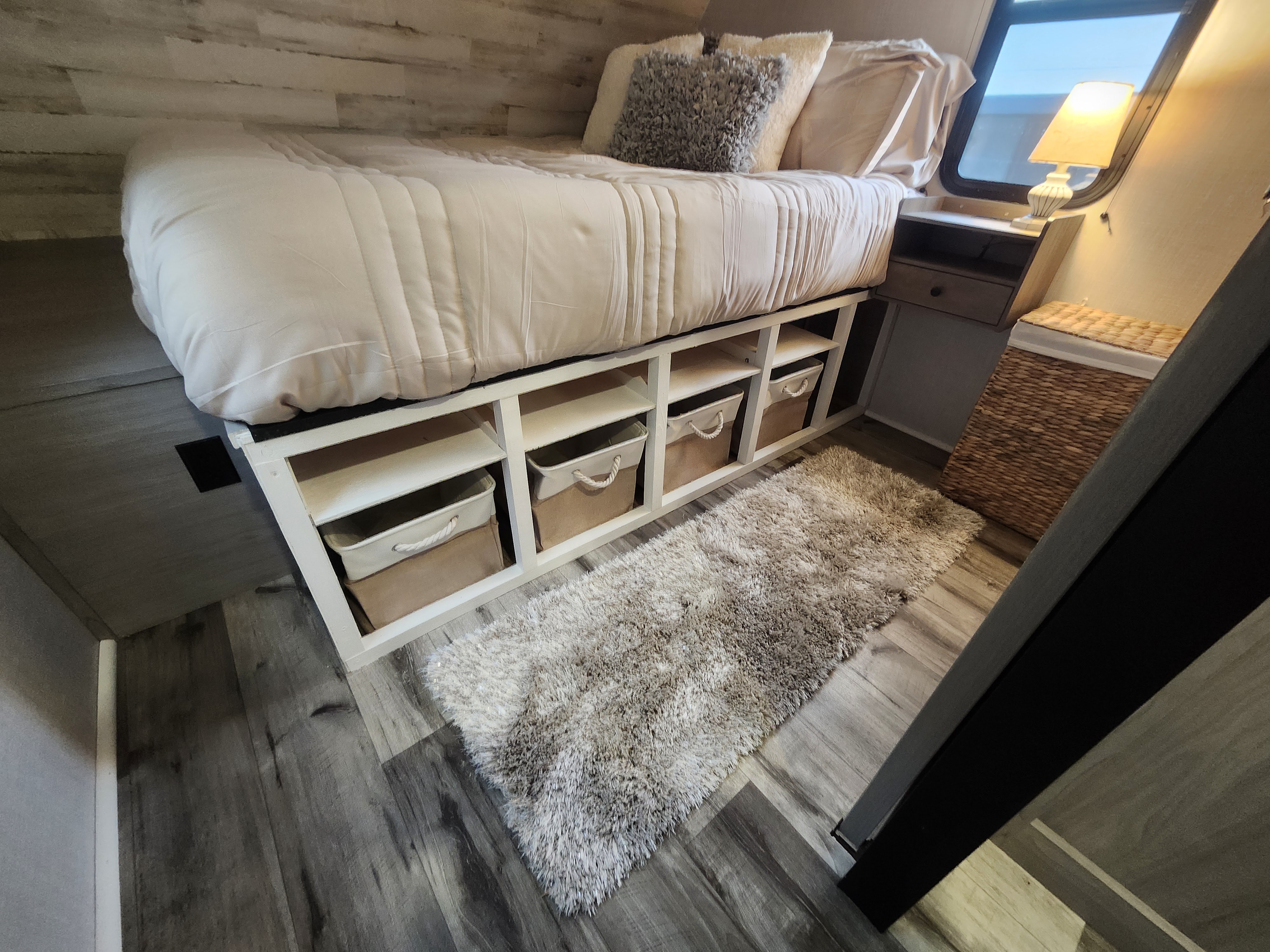 Cozy RV rental bedroom with under-bed storage, a shaggy rug, and a warm lamp, designed for comfortable travel.. Dutchmen Coleman Lantern 2023