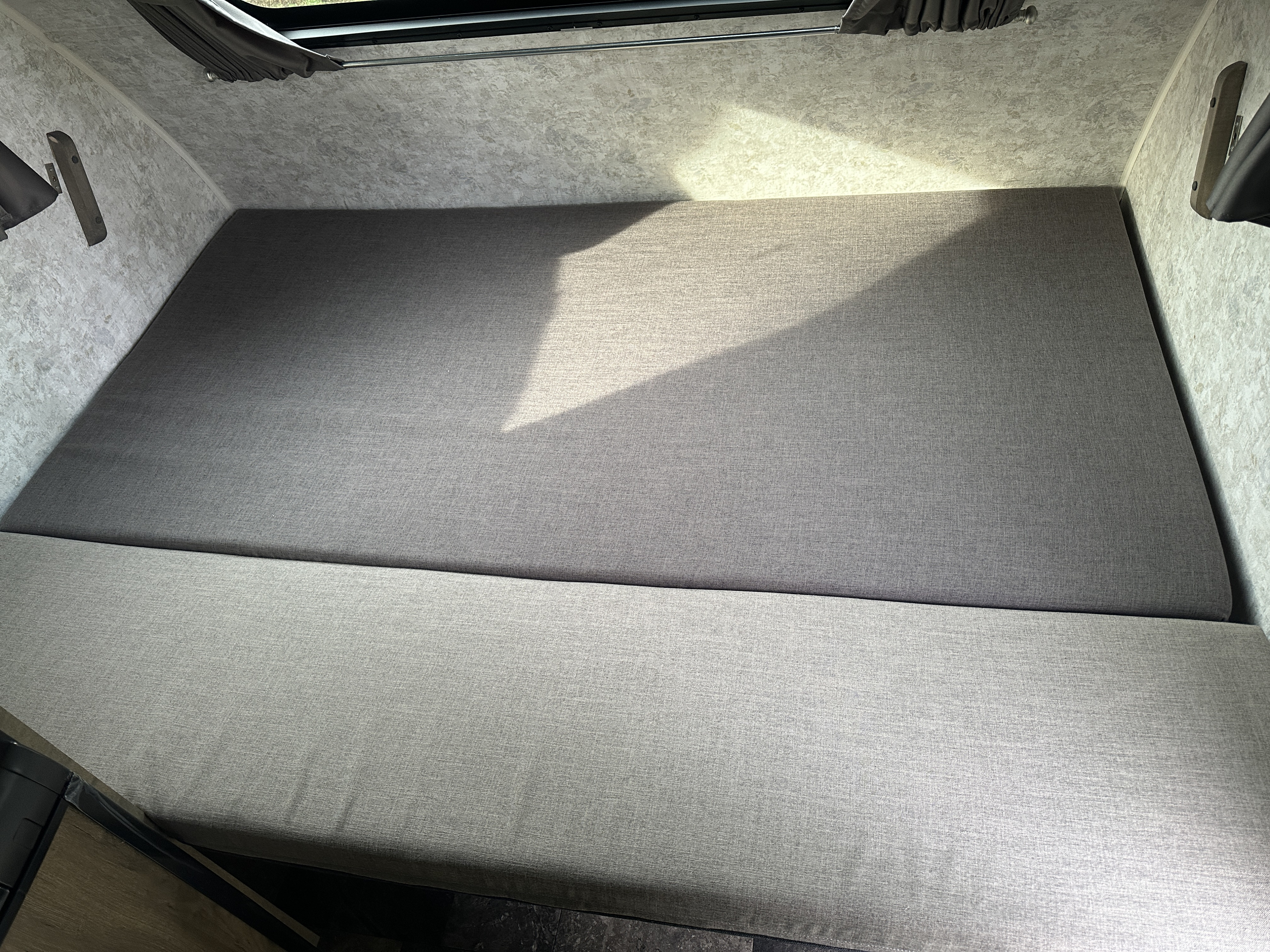 RV rental: Light gray upholstered bed/seating area in a clean, compact camper interior.. Roulettes ProLite Lounge 2024