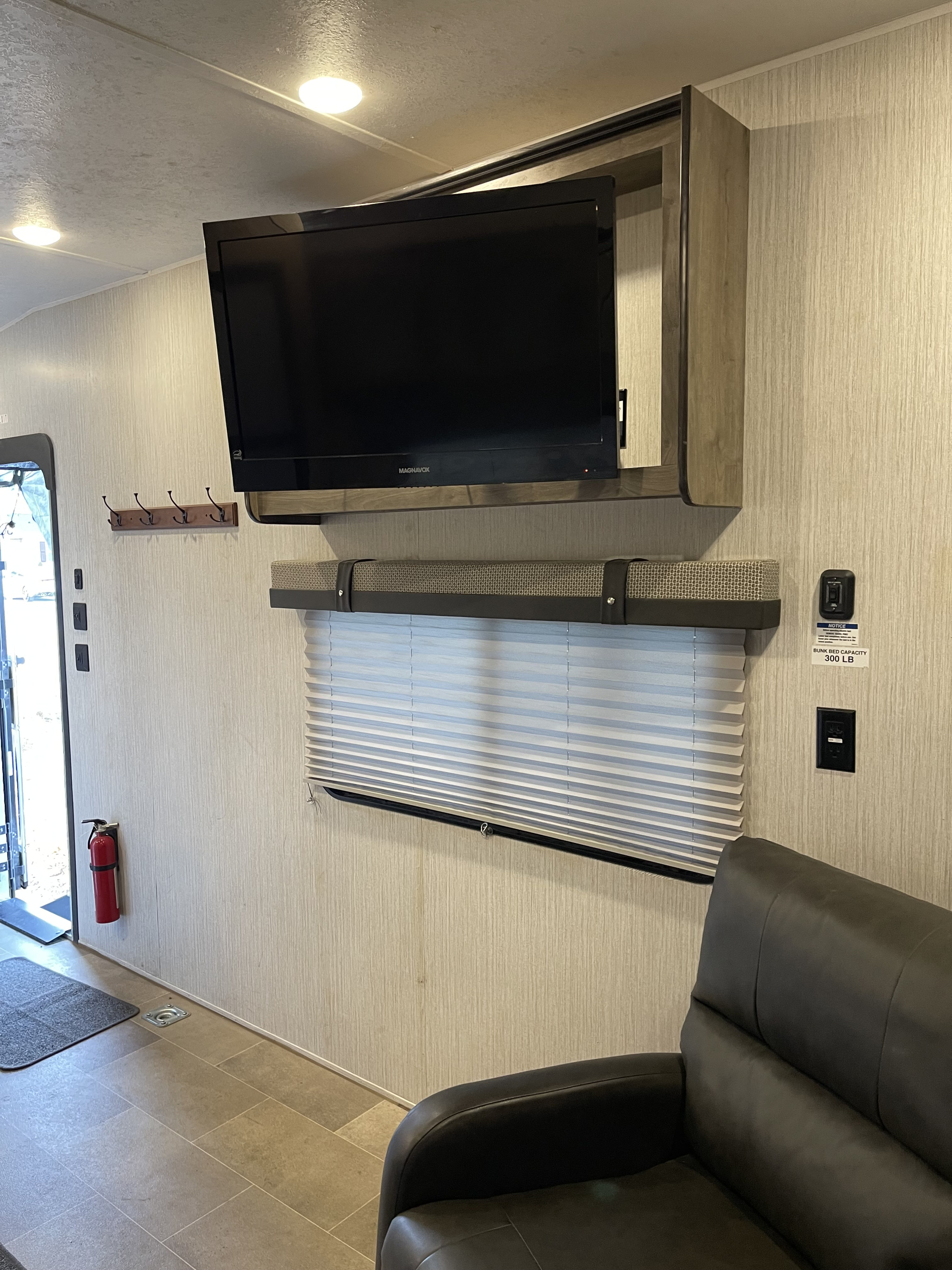 Experience comfort in this RV rental's living space: wall-mounted TV, cozy recliner, window, and practical amenities.. Palomino Puma 2021