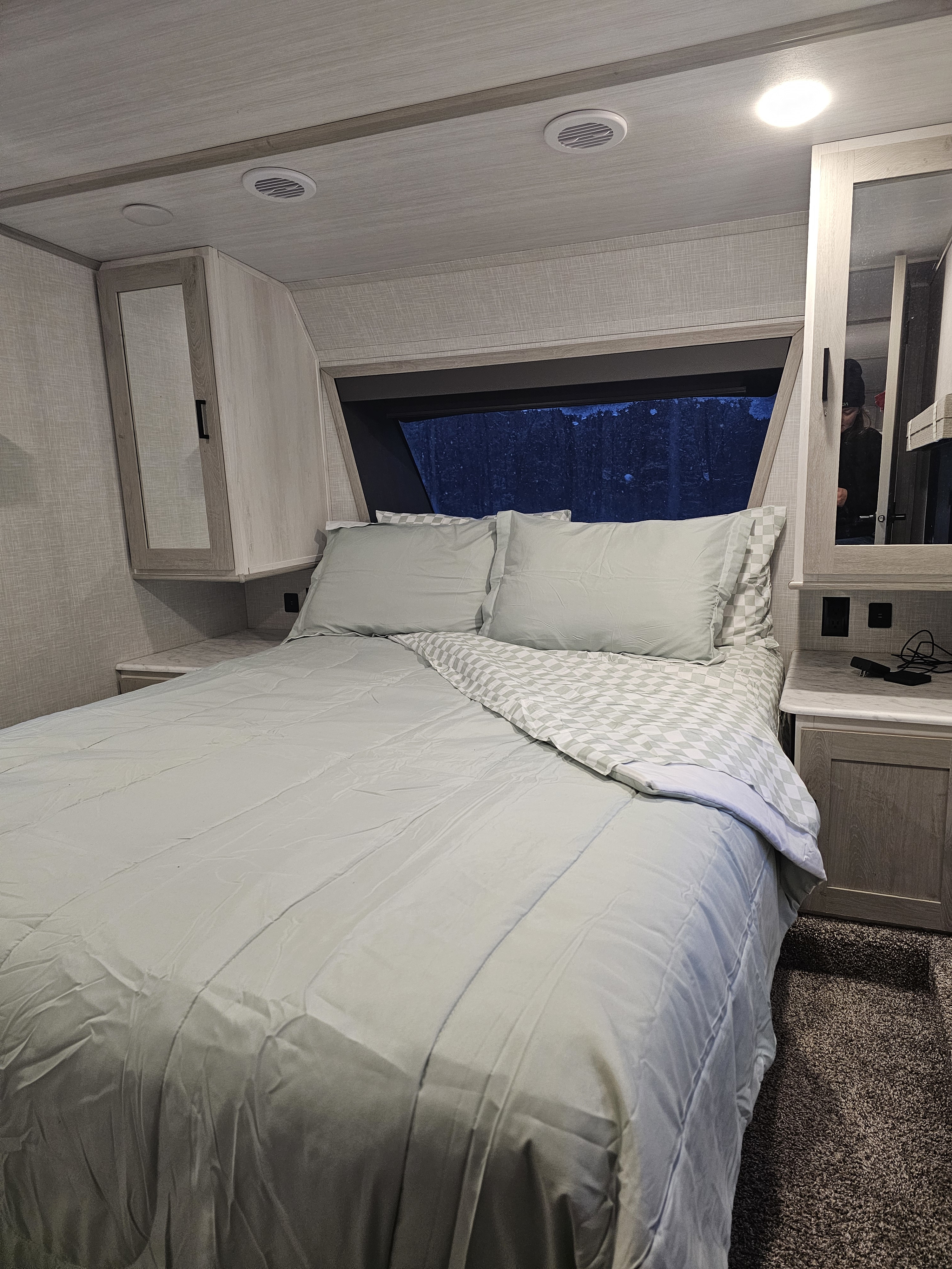 Cozy RV rental bedroom: bed with light green bedding, mirrored cabinets, ceiling vents & window view.. Forest River Impression 2021