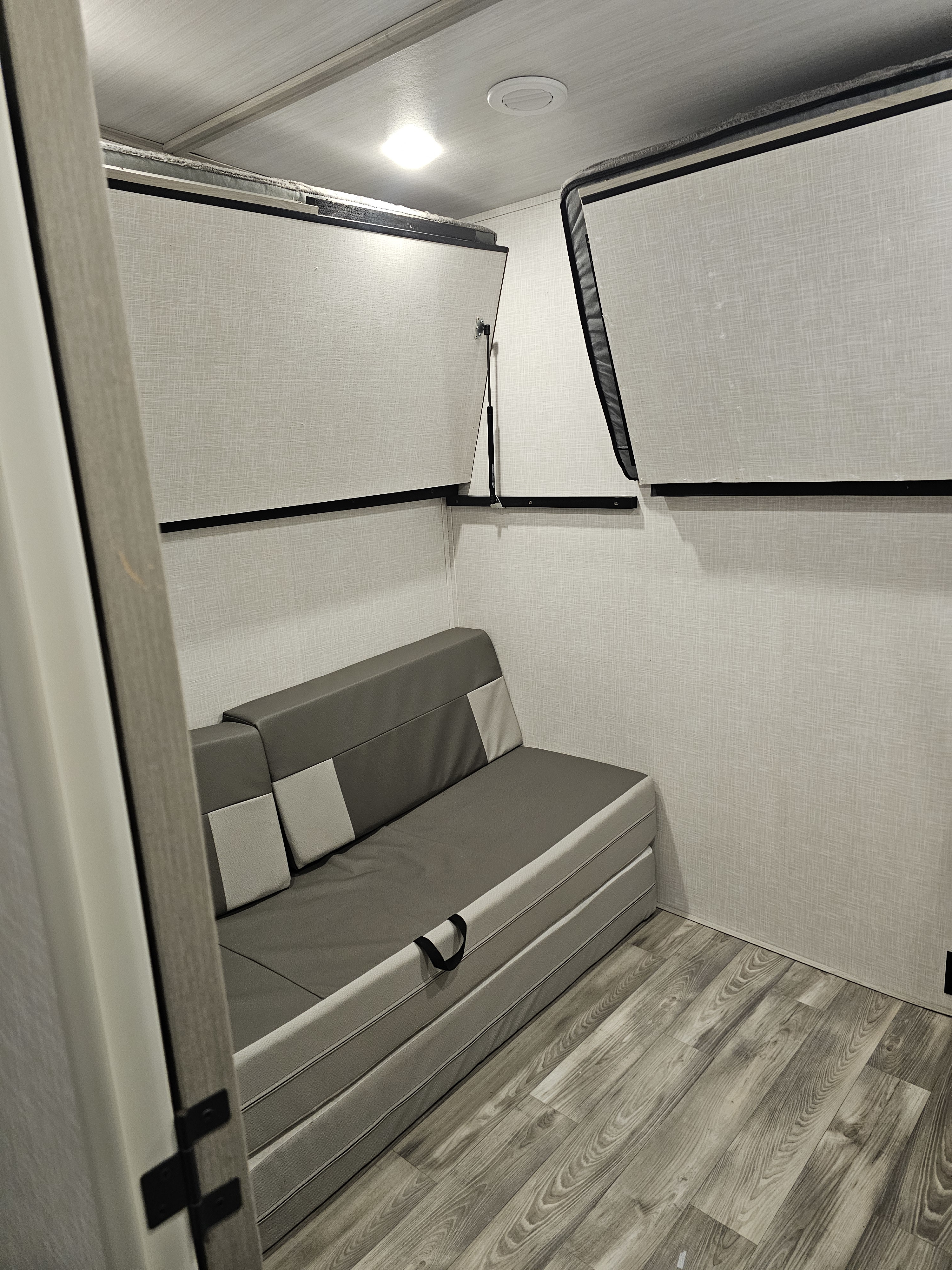 RV rental's compact sleeping area: convertible sofa and two upper fold-down bunk beds.. Forest River Impression 2021