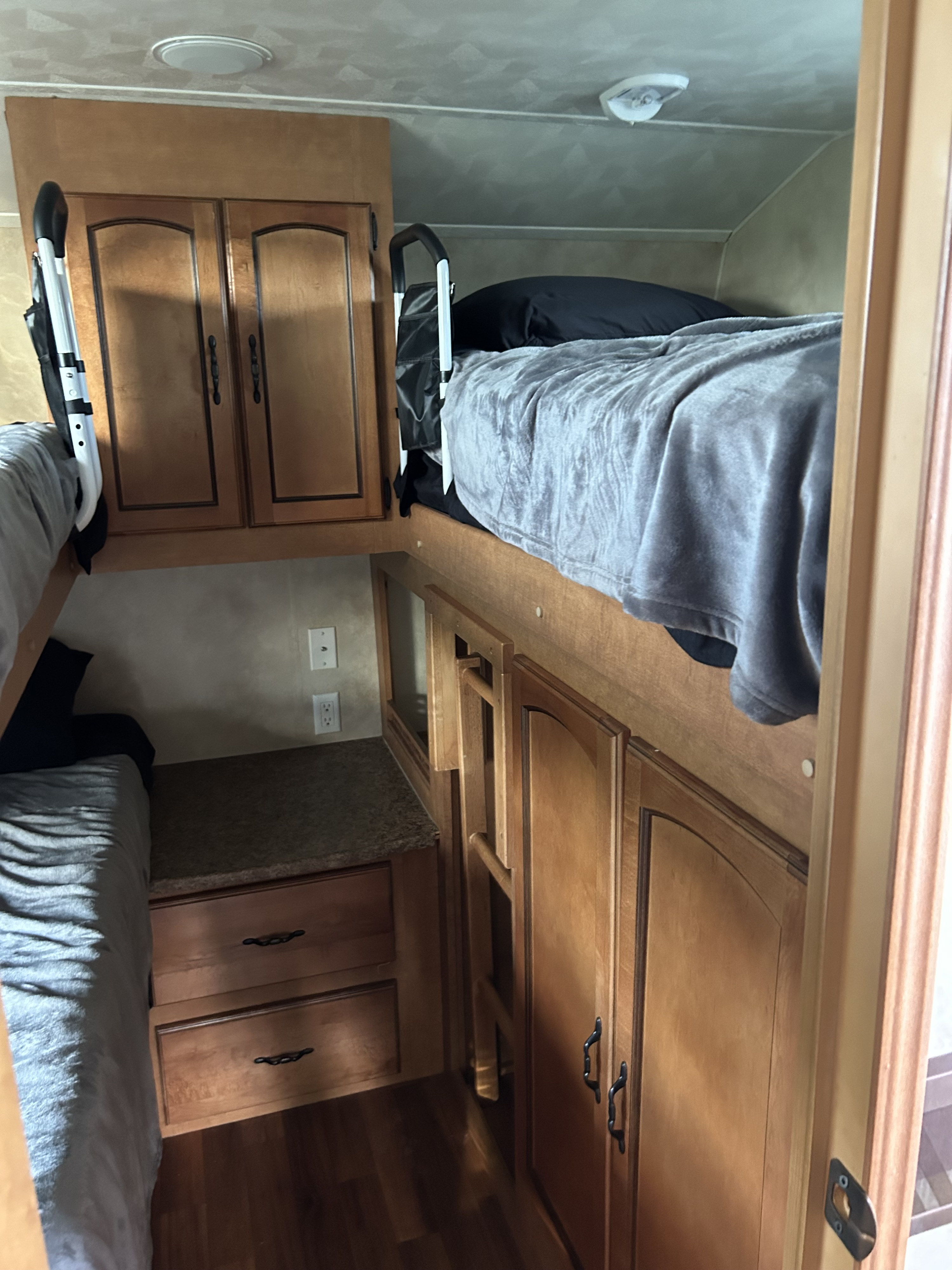 Functional bunk bed setup in an RV rental, featuring wooden storage and power outlets.. Forest River Palomino Puma 2011