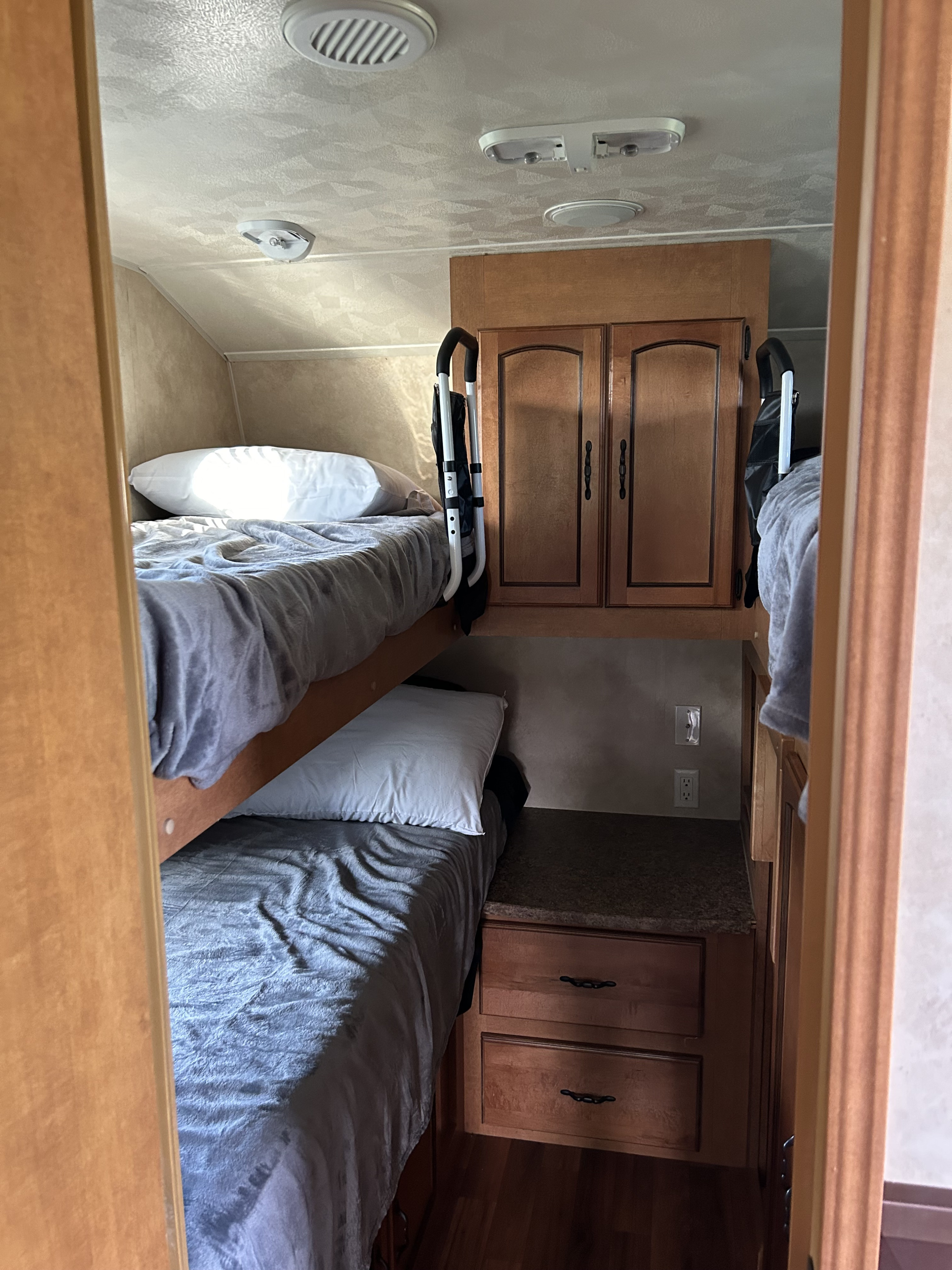 This rv rental features a compact bunk bed sleeping area with storage cabinets, countertop, and overhead lighting for travelers.. Forest River Palomino Puma 2011