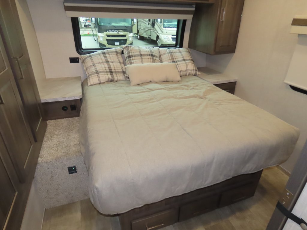 RV rental bedroom: cozy queen bed with storage, nightstands, and window views of other RVs.. Forest River Rockwood Mini Lite 2023