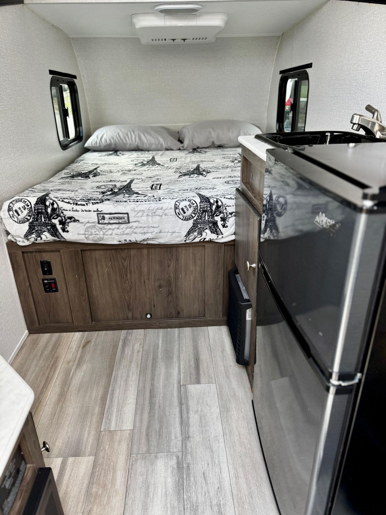Cozy RV rental interior featuring a comfortable bed, compact kitchen with a mini-fridge, and light wood flooring.. Coachmen Viking Express 9.0 2022