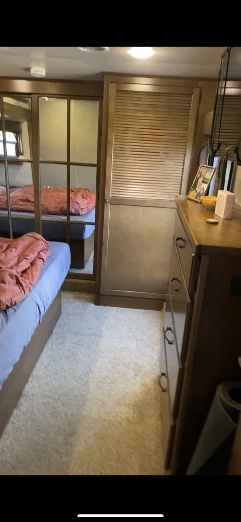 An RV rental bedroom featuring a bed, mirrored closet door, dresser, and carpeted floor with wood accents.. Heartland RVs Bighorn 2015