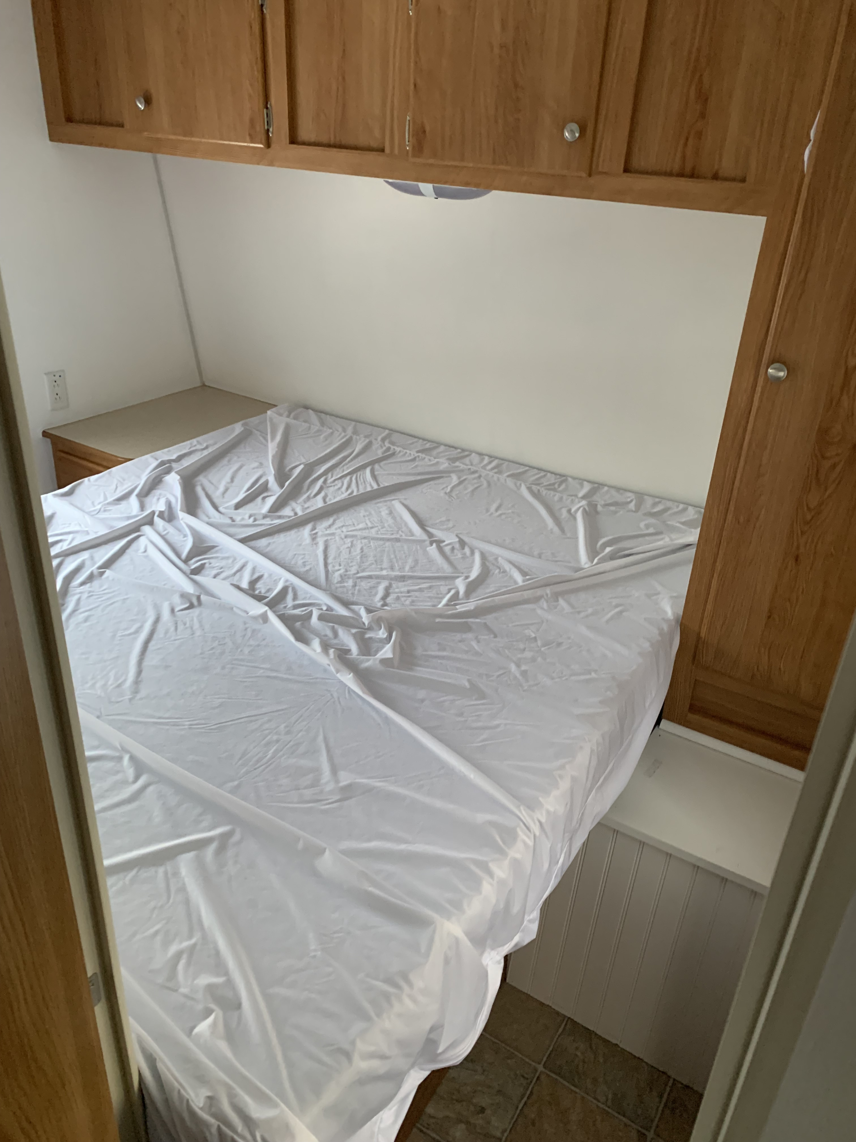 Experience comfort in this RV rental bedroom featuring a covered bed, wooden cabinets, and convenient side counter.. Gulf Stream Kingsport 2007