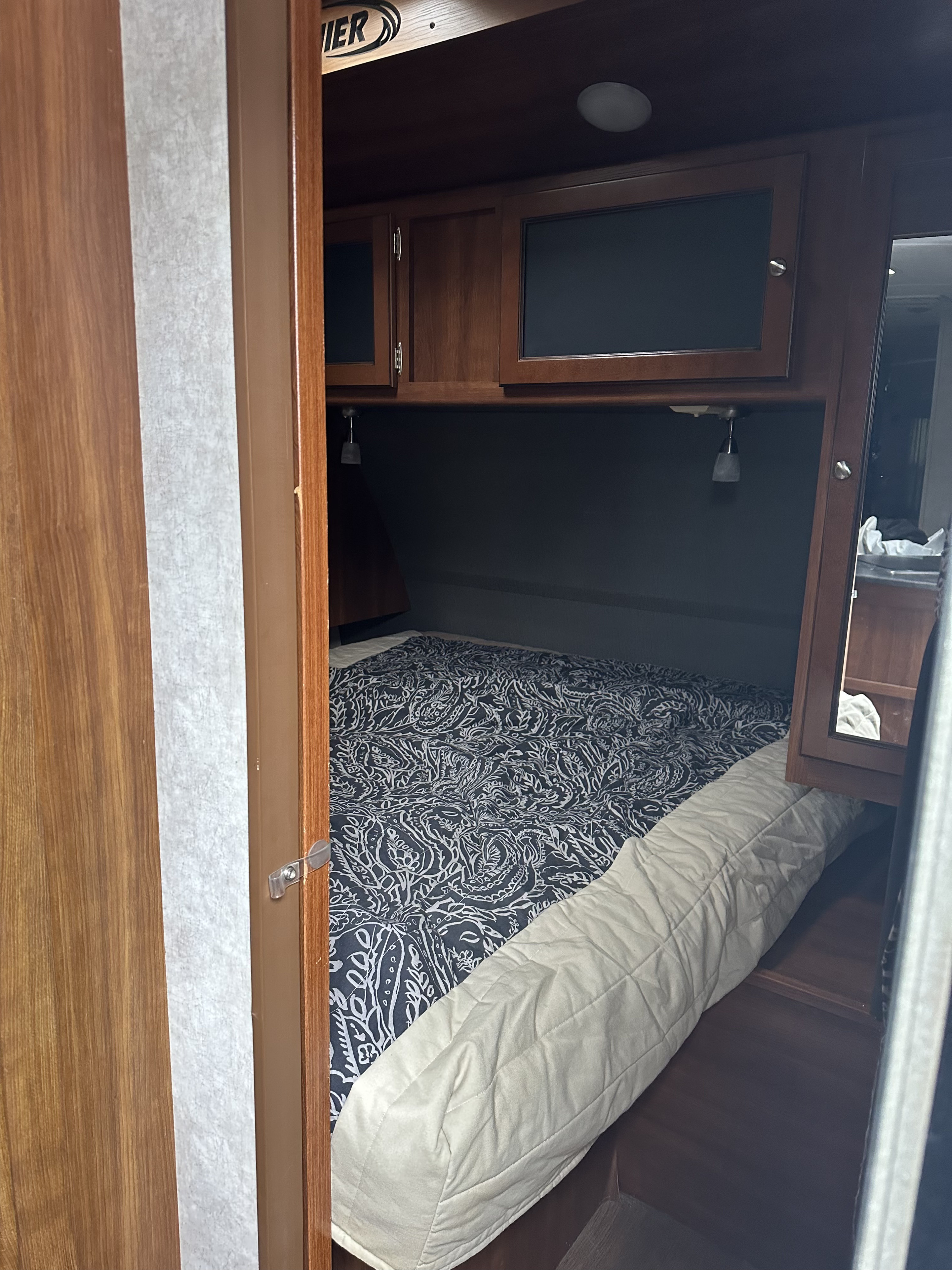 Cozy RV rental bedroom with patterned bedding & overhead storage. Ideal for comfortable travel accommodation.. Keystone RV Bullet Premier Ultra 2014