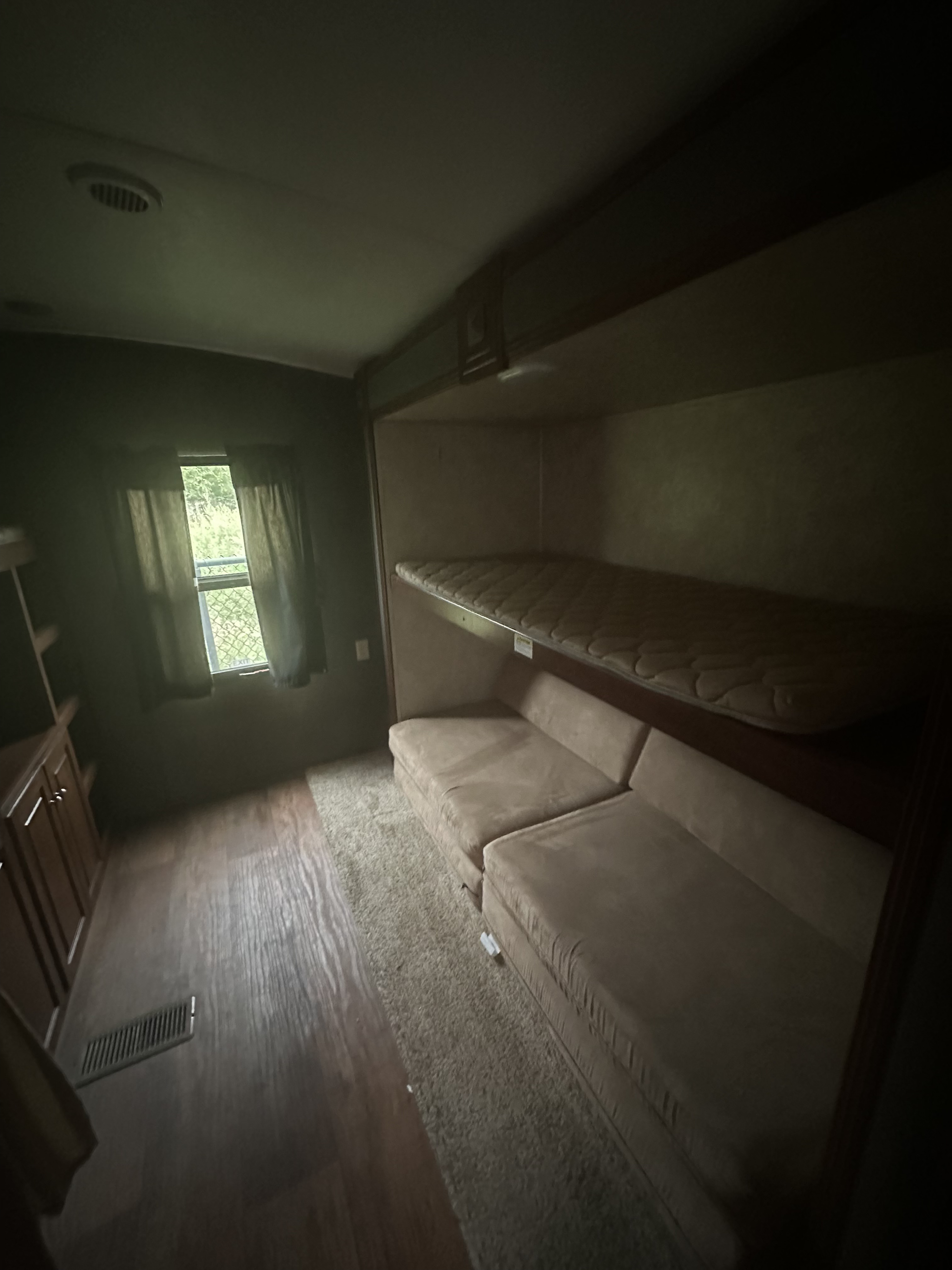 RV rental interior featuring a bunk bed, comfy sofa, and window with outdoor view. Compact, cozy space for travel.. Keystone RV Bullet Premier Ultra 2014