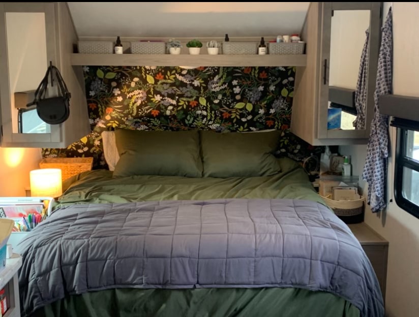 Cozy RV rental bedroom: Features a comfy bed, floral accent wall, and clever storage solutions. Ideal for your next trip.. Dutchmen Coleman Lantern LT 2022