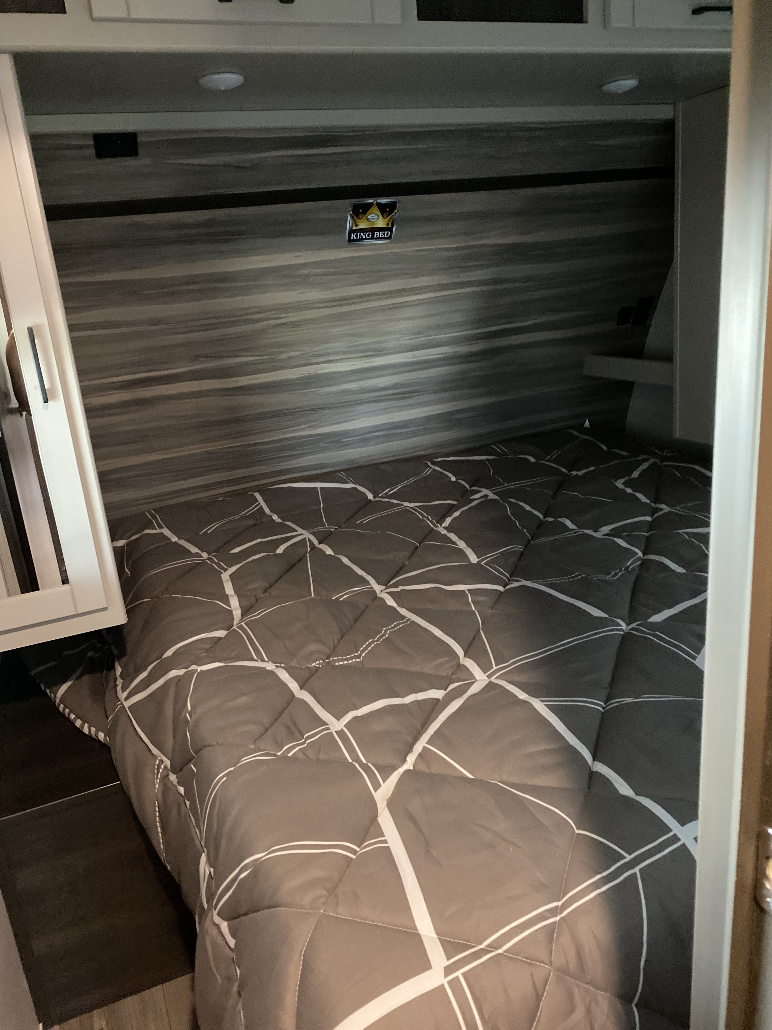 This RV rental features a comfortable king bed with a gray comforter and modern patterned walls, perfect for travelers.. Keystone RV Other 2021