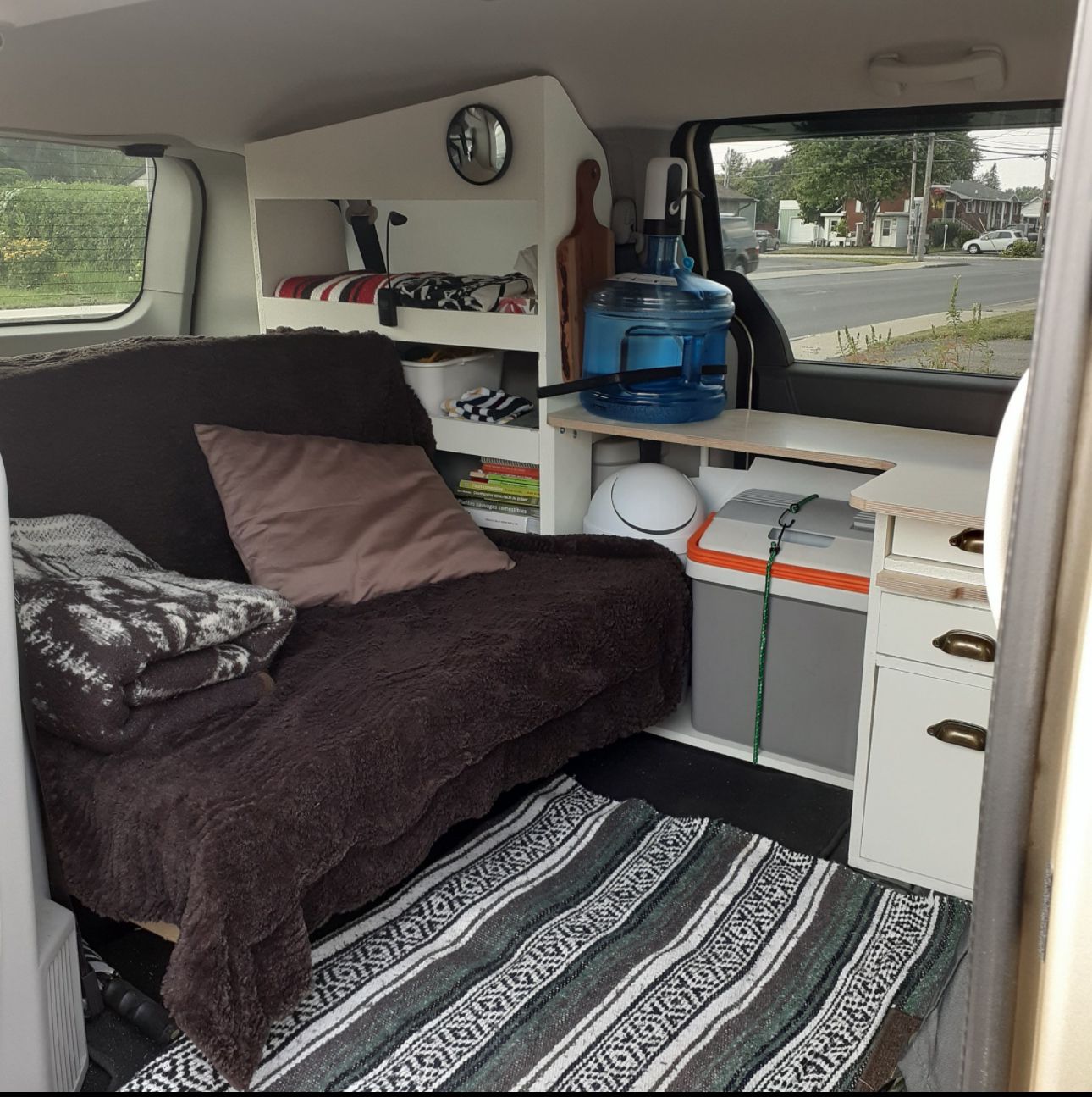 Inside a compact rv rental: a cozy bed/sofa, smart storage, water dispenser, and mini-fridge for comfortable travel.. Dodge 24ft 2010