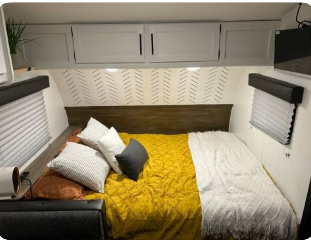 Cozy RV rental bedroom with white cabinets, patterned wall, and a comfortable bed. Perfect for your next adventure.. Forest River Cherokee Wolf Pup 2022