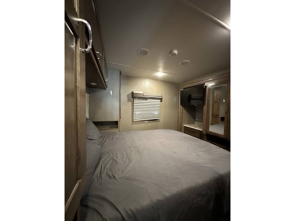 RV rental: Comfortable bedroom with a large bed, mounted TV, overhead cabinets, and a mirrored closet door.. Winnebago Intent 2018
