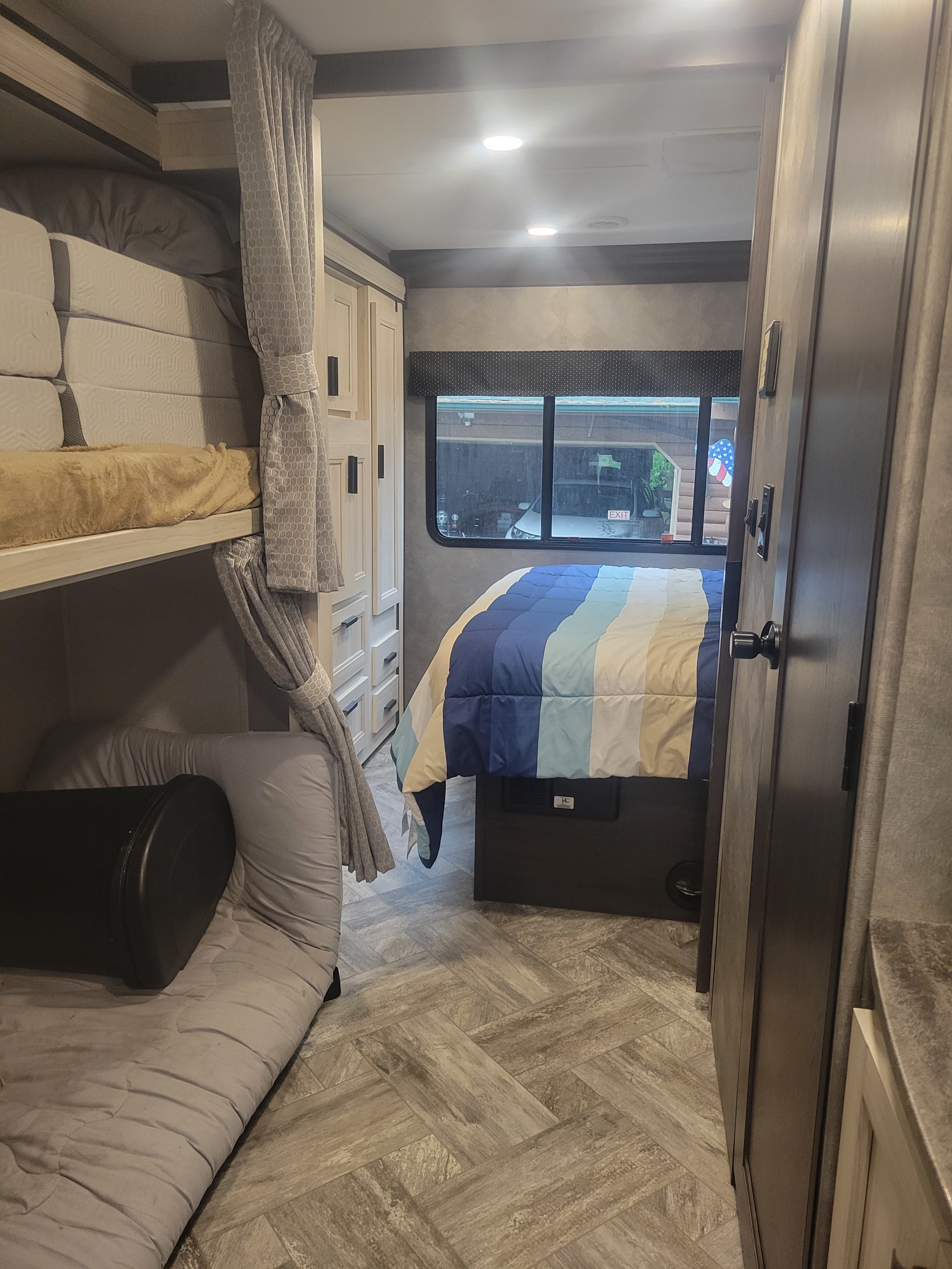 RV rental interior features bunk beds, light wood cabinetry, and a main bed with a striped comforter.. Forester LE 2021