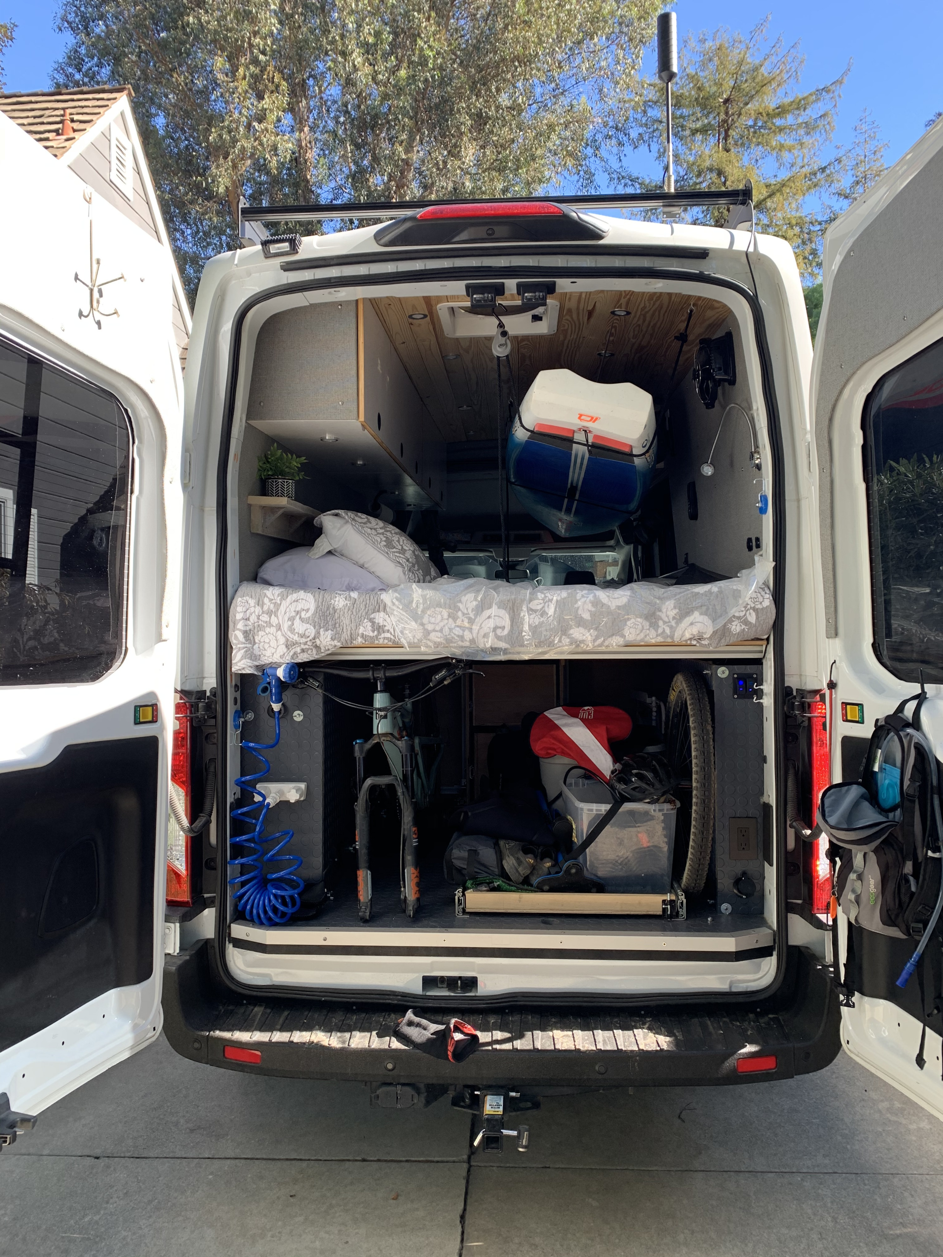 This RV rental campervan's rear reveals a cozy bed, bike storage, kayak, and gear for adventure-ready road trips.. Ford Custom Transit 2019