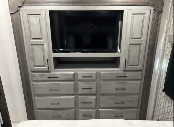 RV rental bedroom with integrated TV, storage cabinets, and ample drawers. A functional and stylish interior for your trip.. Heartland RVs Landmark 365 2021
