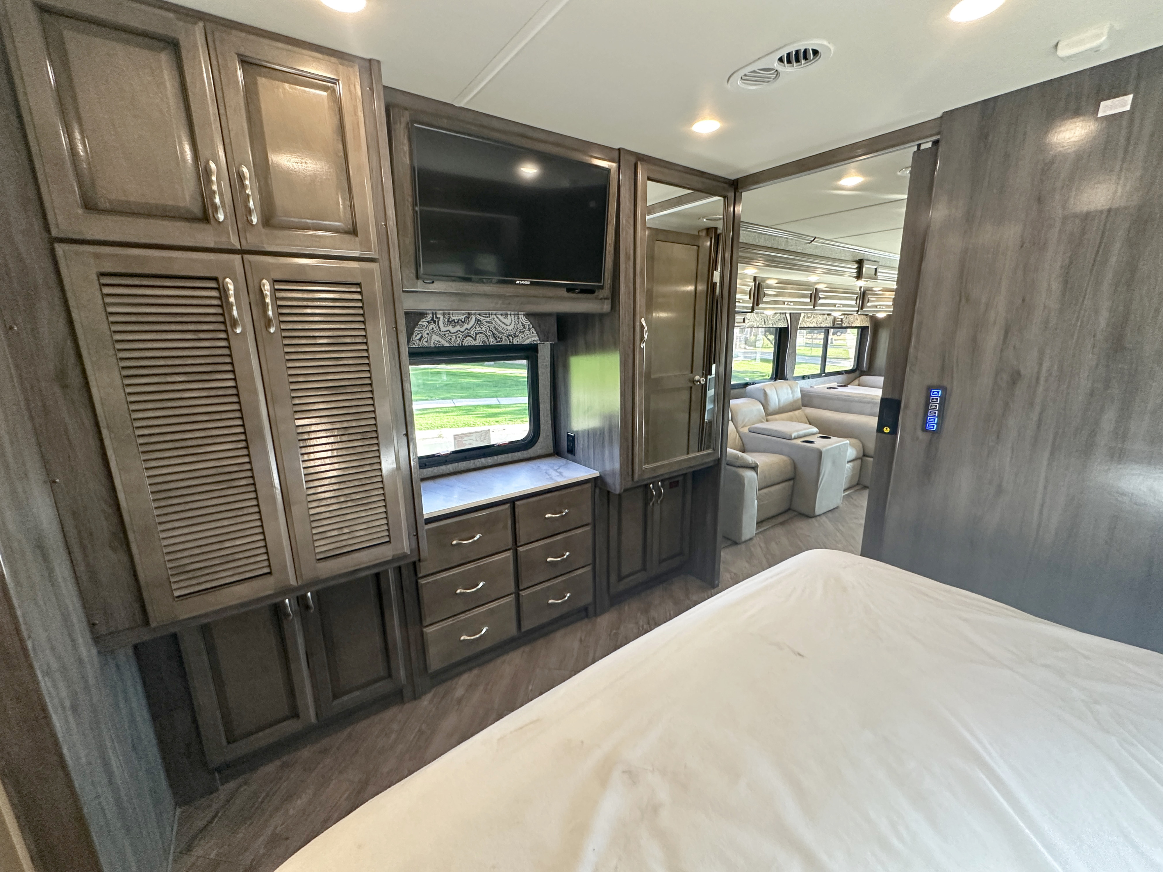 RV rental bedroom features built-in cabinets, TV, and connects to a living area with recliners.. Fleetwood Bounder 2018