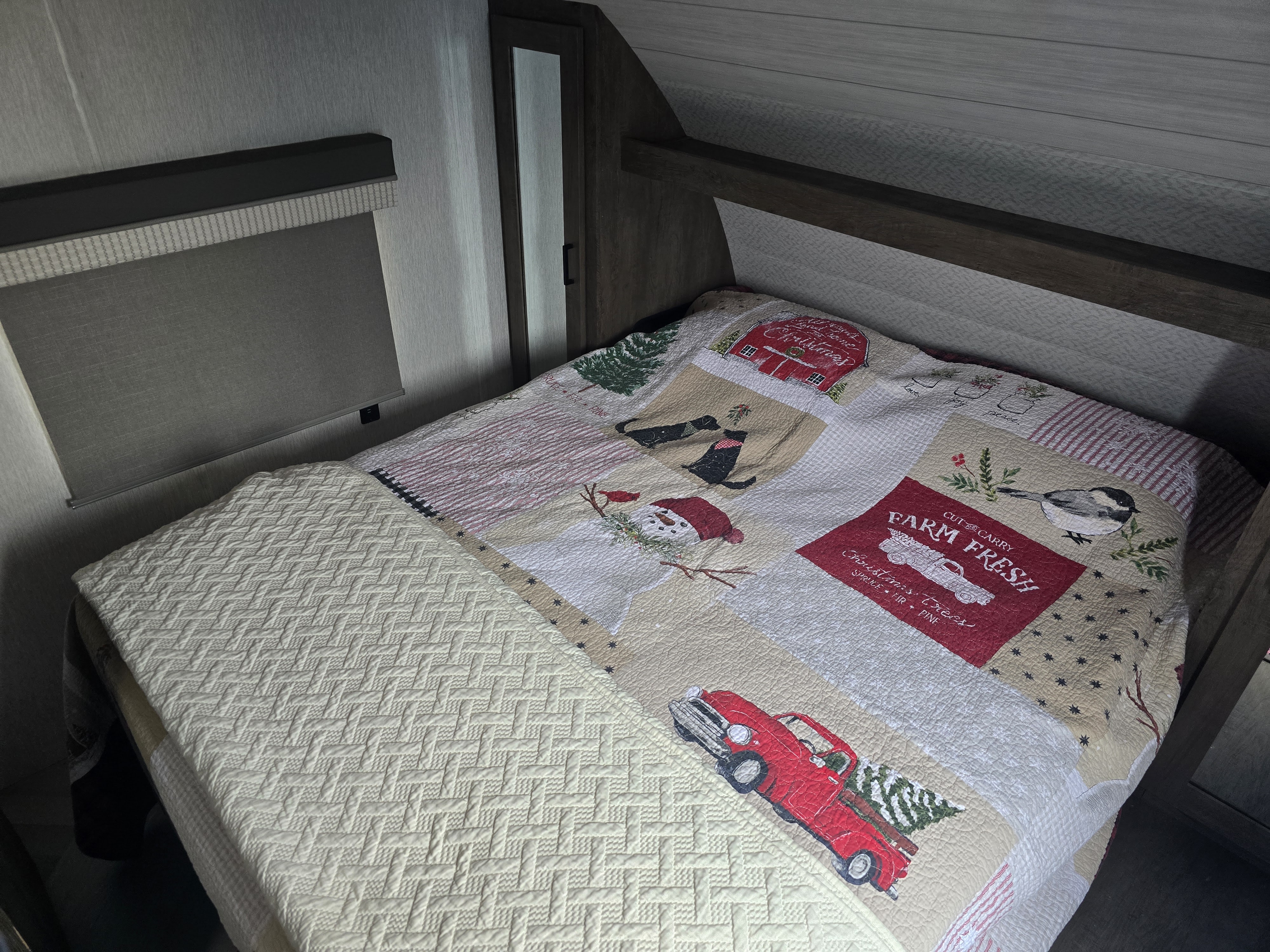 RV rental bedroom featuring a festive Christmas quilt and a cozy patterned blanket on the bed, ready for holiday travel.. Forest River Wildwood X-Lite 2022