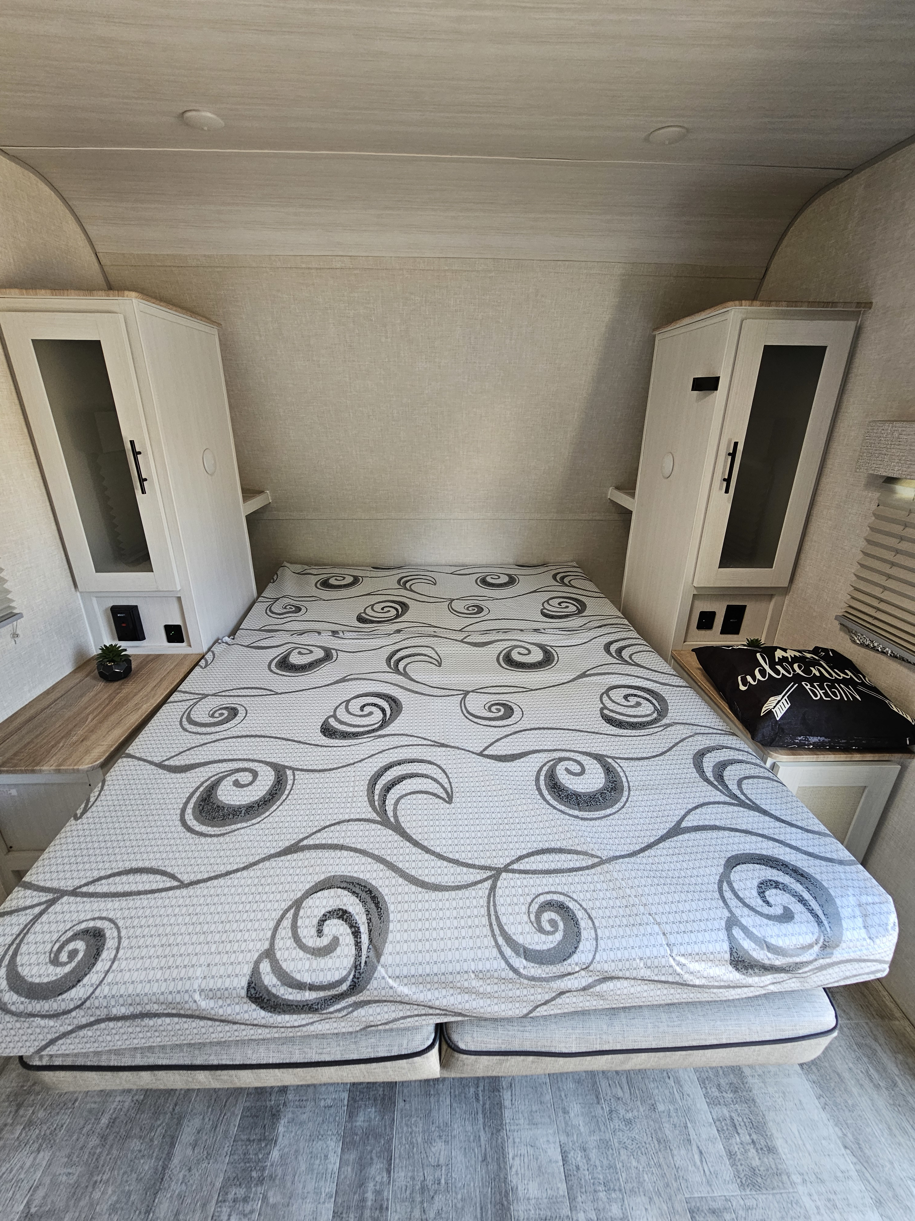 Inside an RV rental: a cozy bedroom features a patterned mattress, side cabinets, and nightstands, inviting adventure.. Forest River No Boundaries NB20.3 Essentials Only 2023