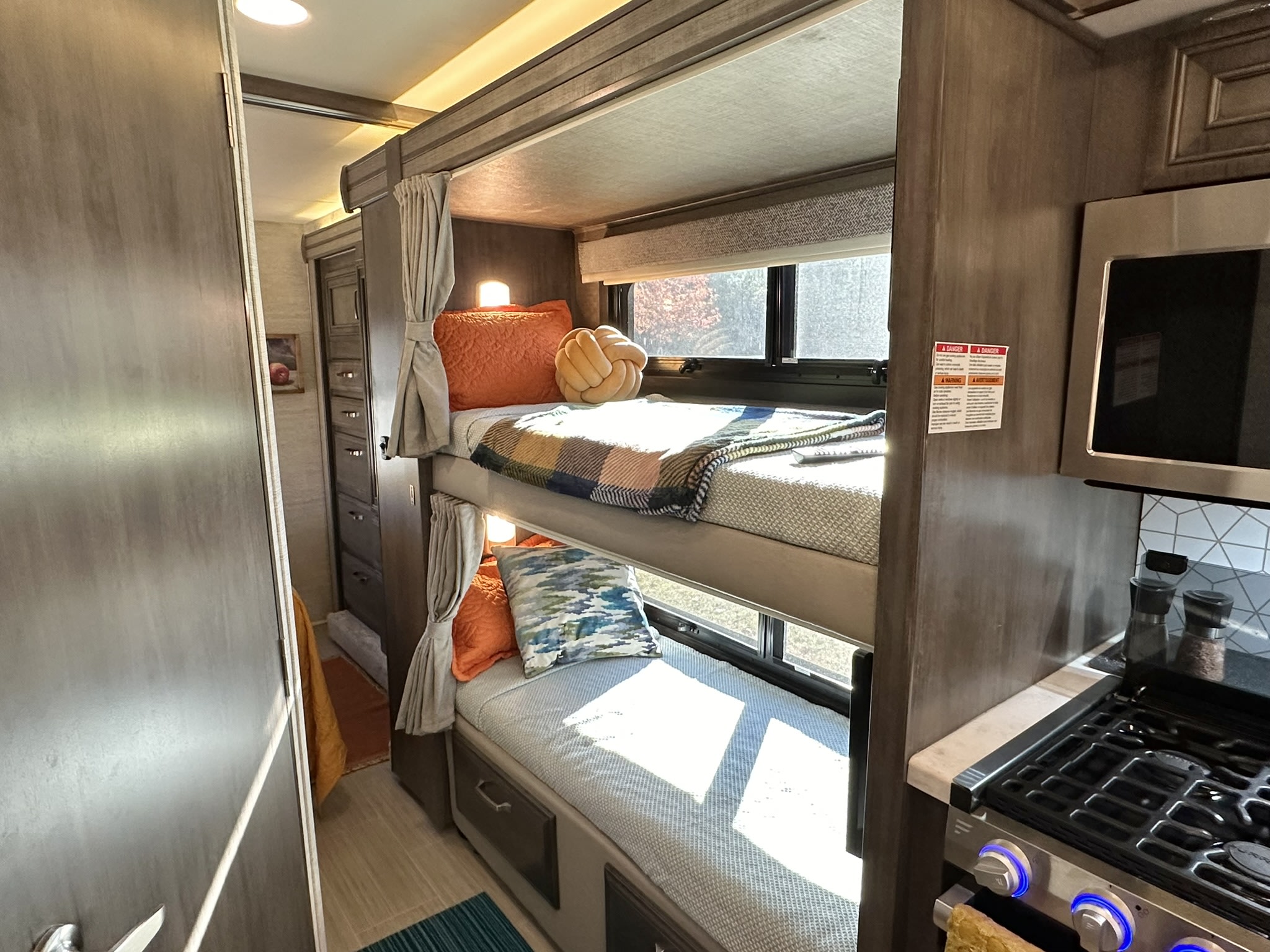 Cozy RV rental interior with bunk beds, a compact kitchen, and sunlit windows.. Entegra Coach Esteem 2023