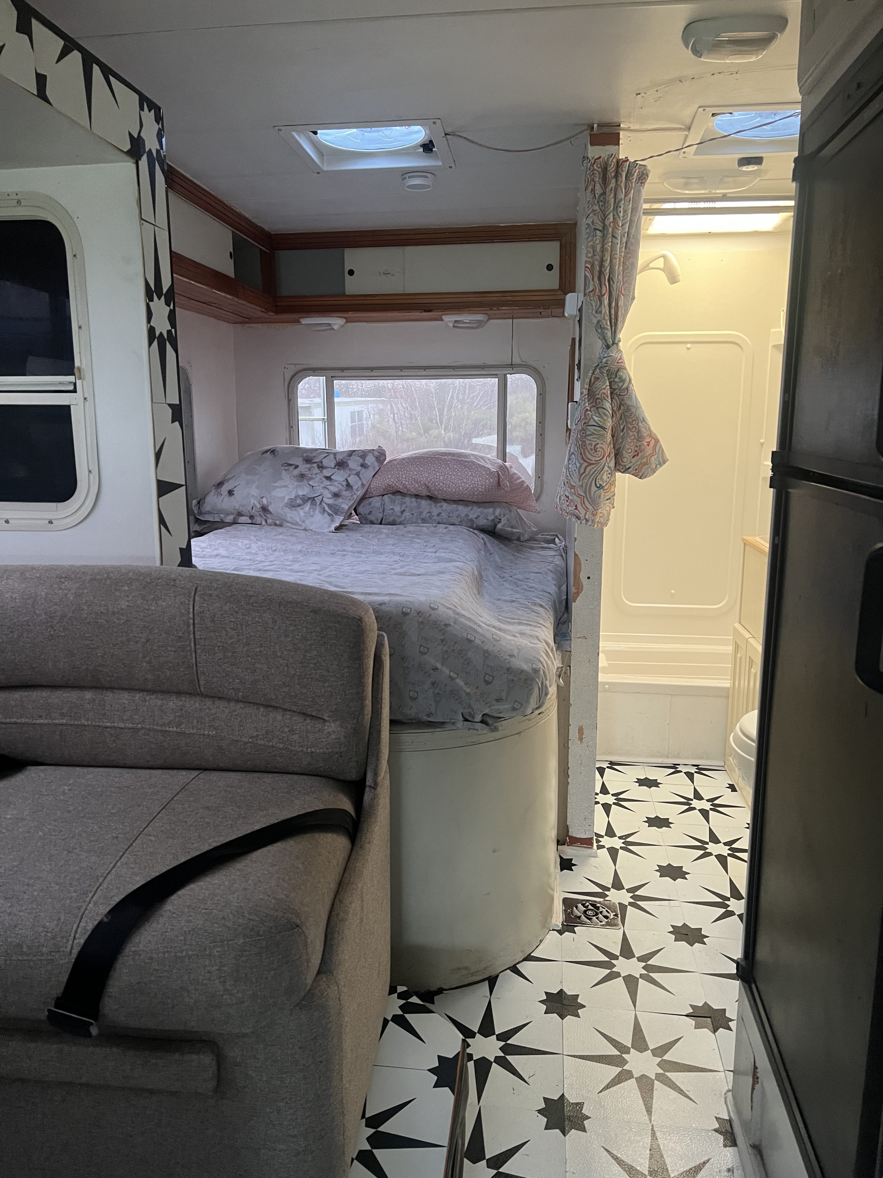 This RV rental features a comfortable bed, sofa with seatbelt, and a compact shower/toilet area on star-patterned flooring.. Coachmen Freelander 2008