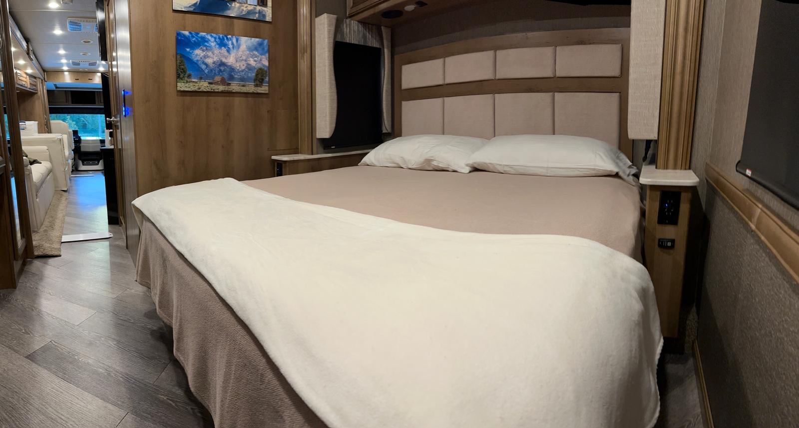 Step inside this cozy RV rental's bedroom! Featuring a queen bed, stylish headboard, and access to the front cabin.. Fleetwood Bounder 33C 2021