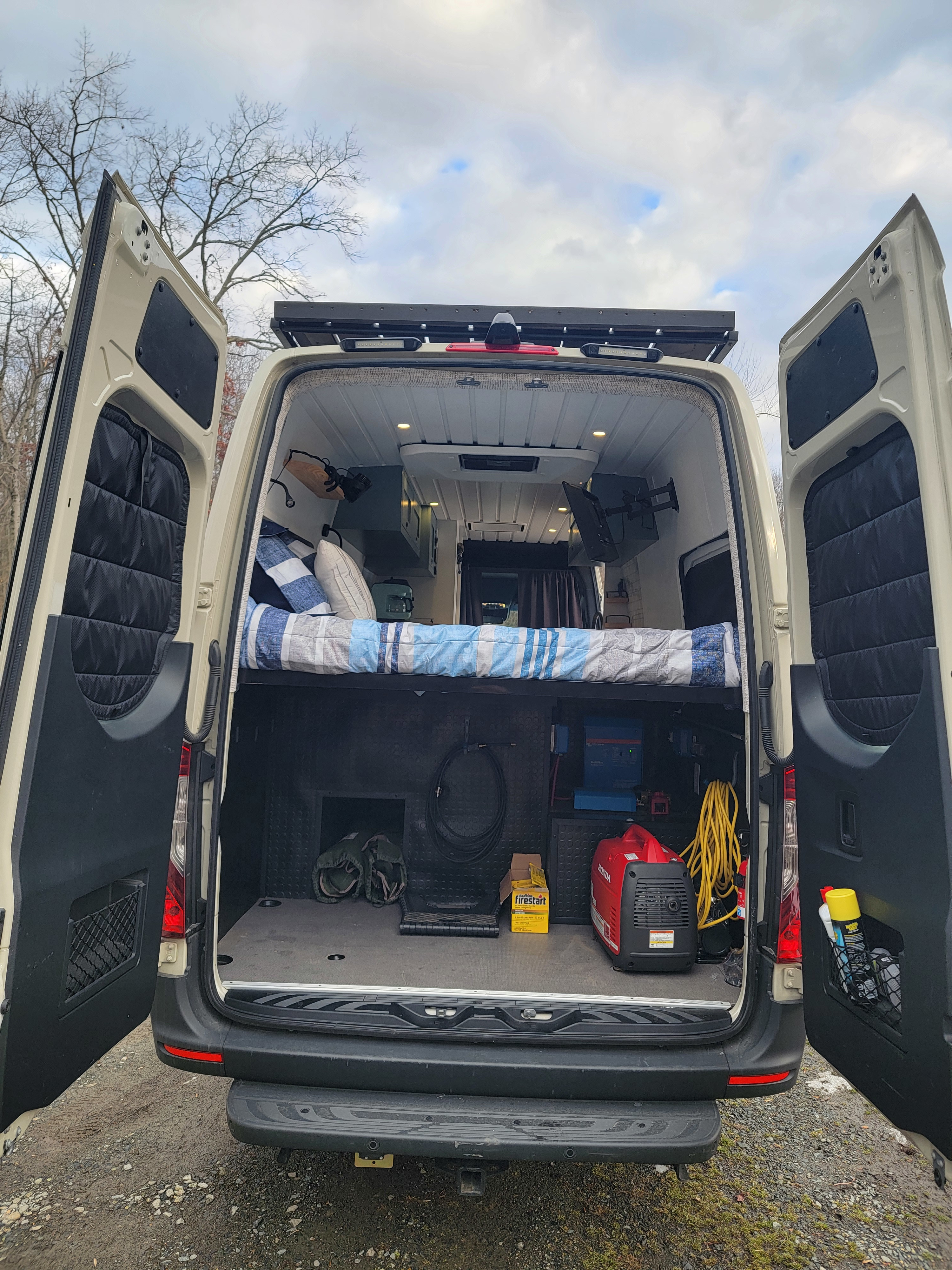 RV rental interior: This camper van offers a cozy bed, ample storage with a Honda generator, and rear door access.. Mercedes-Benz Sprinter 2022