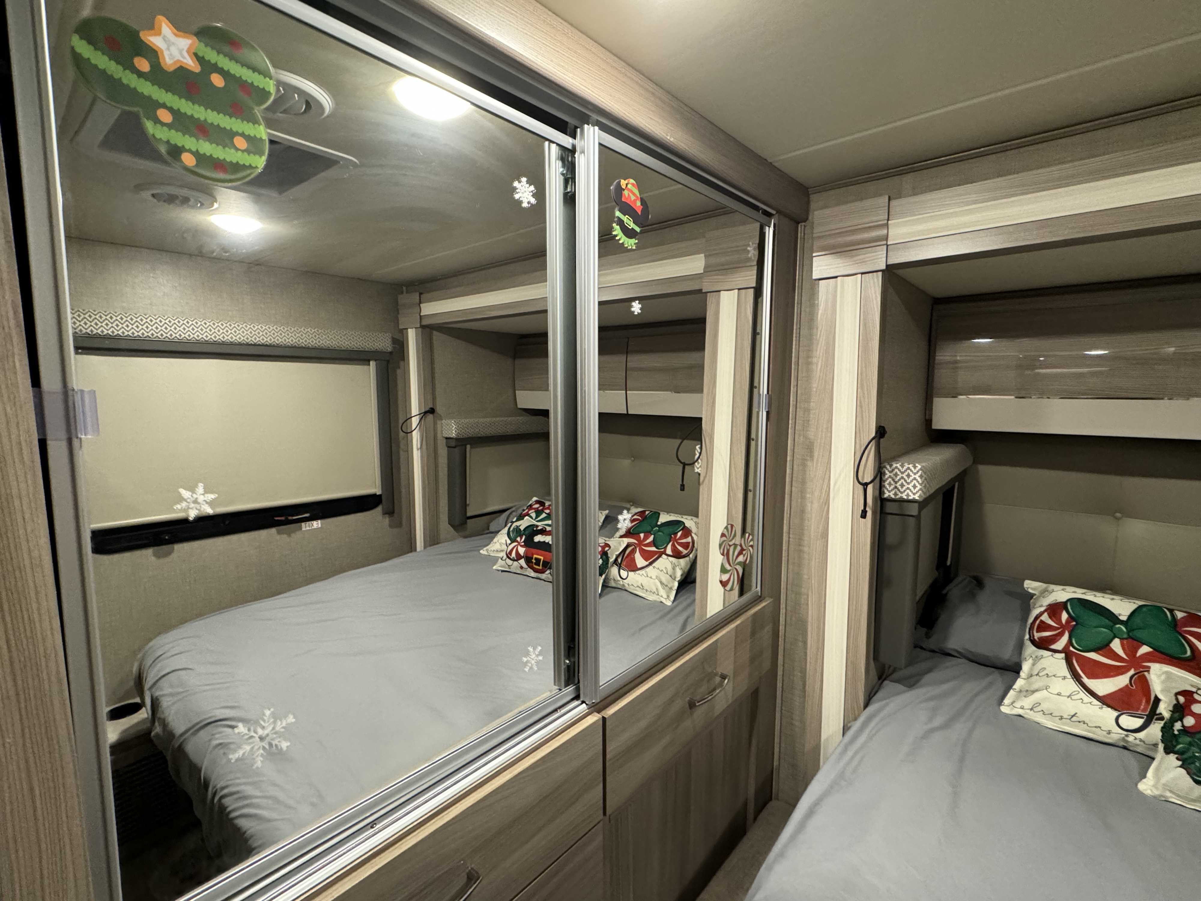 RV rental interior showing a cozy bedroom with two beds, festive Mickey-themed decor, and a mirrored sliding closet.. Mercedes Tiburon 2021