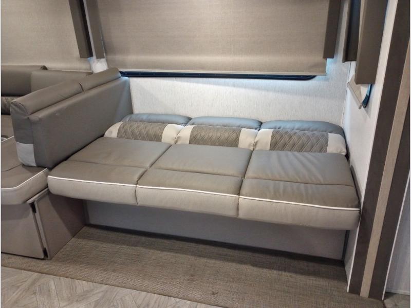 Modern grey sofa converted to a bed inside an RV rental, offering comfortable and versatile sleeping space.. Forest River Wildwood 2023