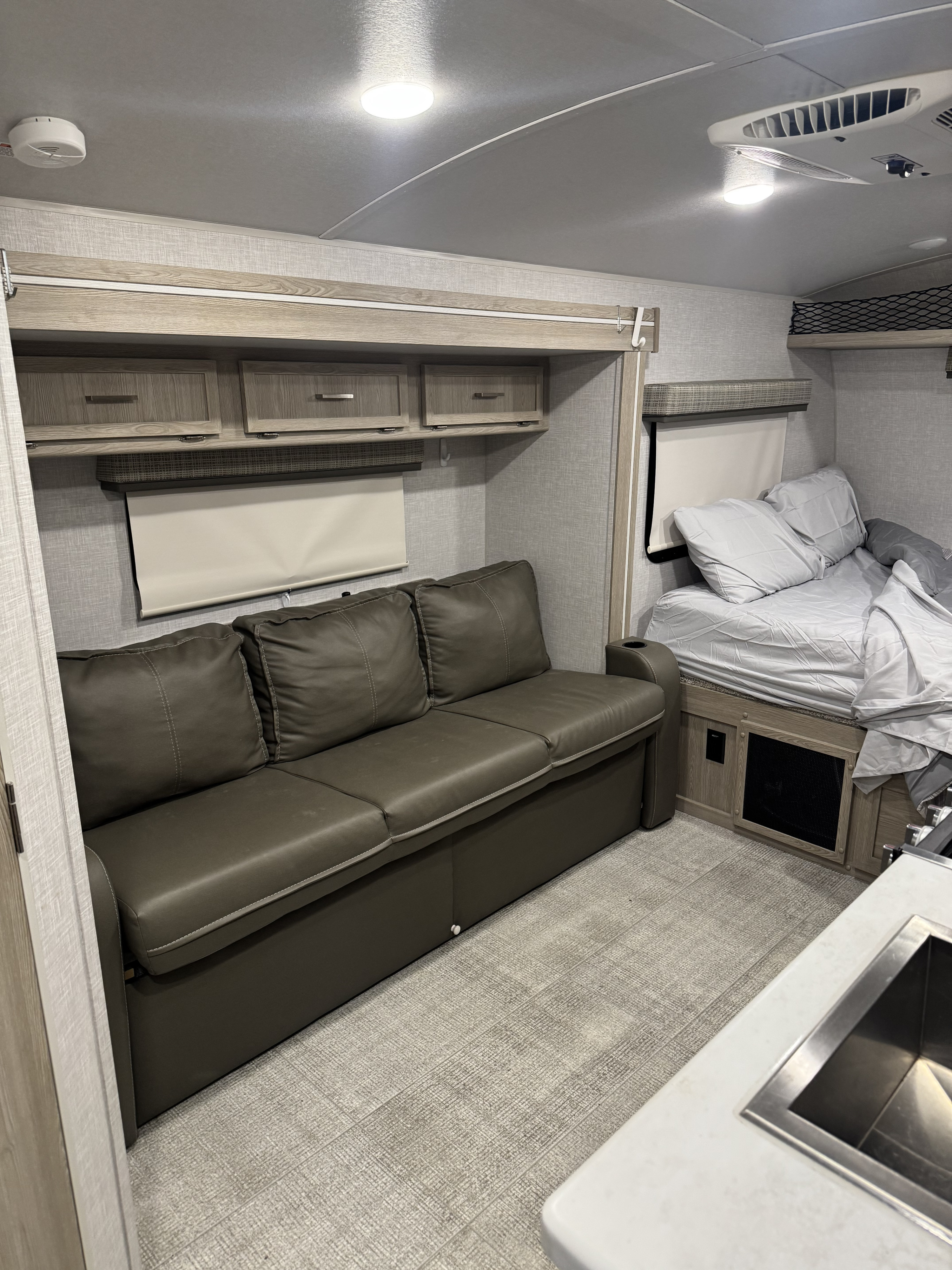 RV rental interior: inviting sofa, bed, overhead storage, and a compact kitchen sink visible. Experience cozy travel comfort.. Forest River Flagstaff E-Pro 2021