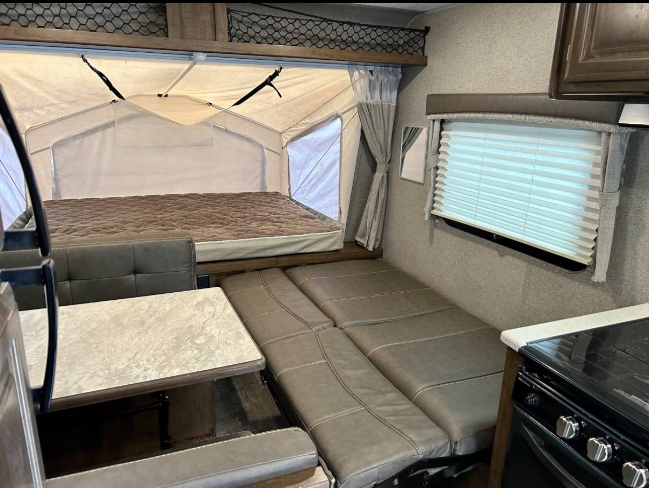 Inside this RV rental: a large pop-out bed, convertible dinette, and kitchen area. Perfect for comfortable travels.. Forest River Rockwood Roo 2019