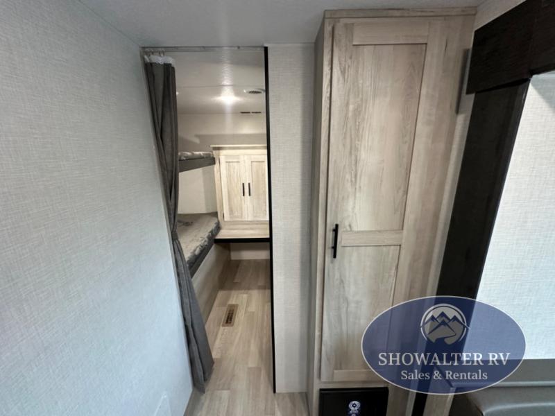 This RV rental interior features spacious bunk beds, a handy wardrobe, and light wood flooring, ideal for a camper trip.. KZ Sportsmen SE 301BHKSE 2025