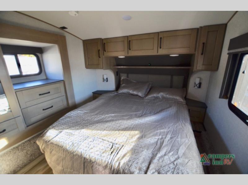 Experience comfort in this RV rental's spacious bedroom interior, complete with a cozy bed, storage, and natural light.. Grand Design Reflection 2023
