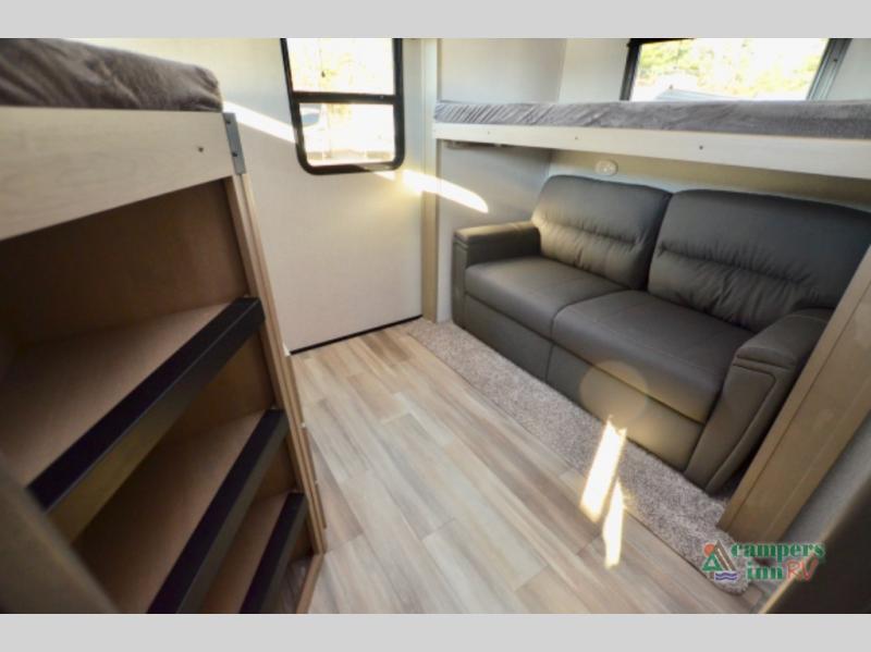 Cozy RV rental interior with a dark sofa, bunk beds, and light wood flooring for comfortable travel.. Grand Design Reflection 2023