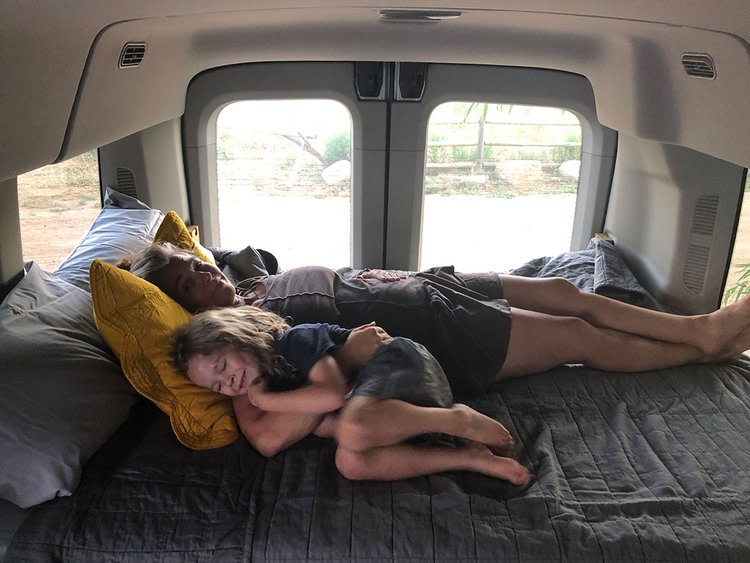 Inside their RV rental, an adult and child relax on a cozy bed. Perfect family travel in a spacious camper van.. Ford Transit Custom 2015