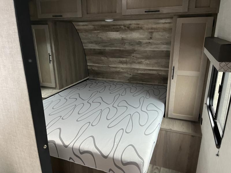 Inside an RV rental, this cozy bedroom features a bed with patterned mattress, wood accents, & ample storage.. Gulf Stream Innsbruck 2022