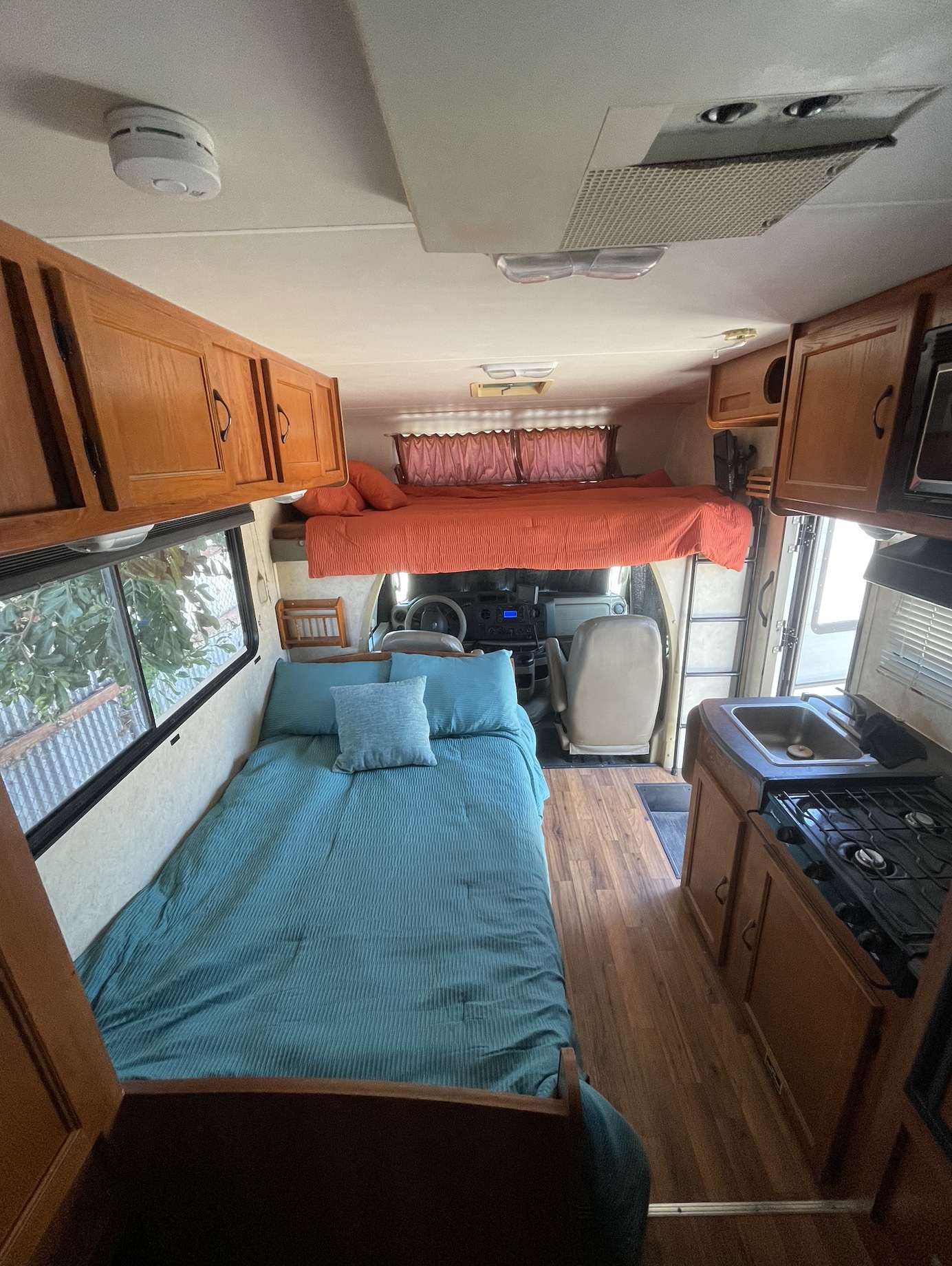 Bright RV rental interior with teal and orange beds, full kitchen, and storage, offering a comfortable living space.. Freelander Coachmen 21qb Ford 350 2011
