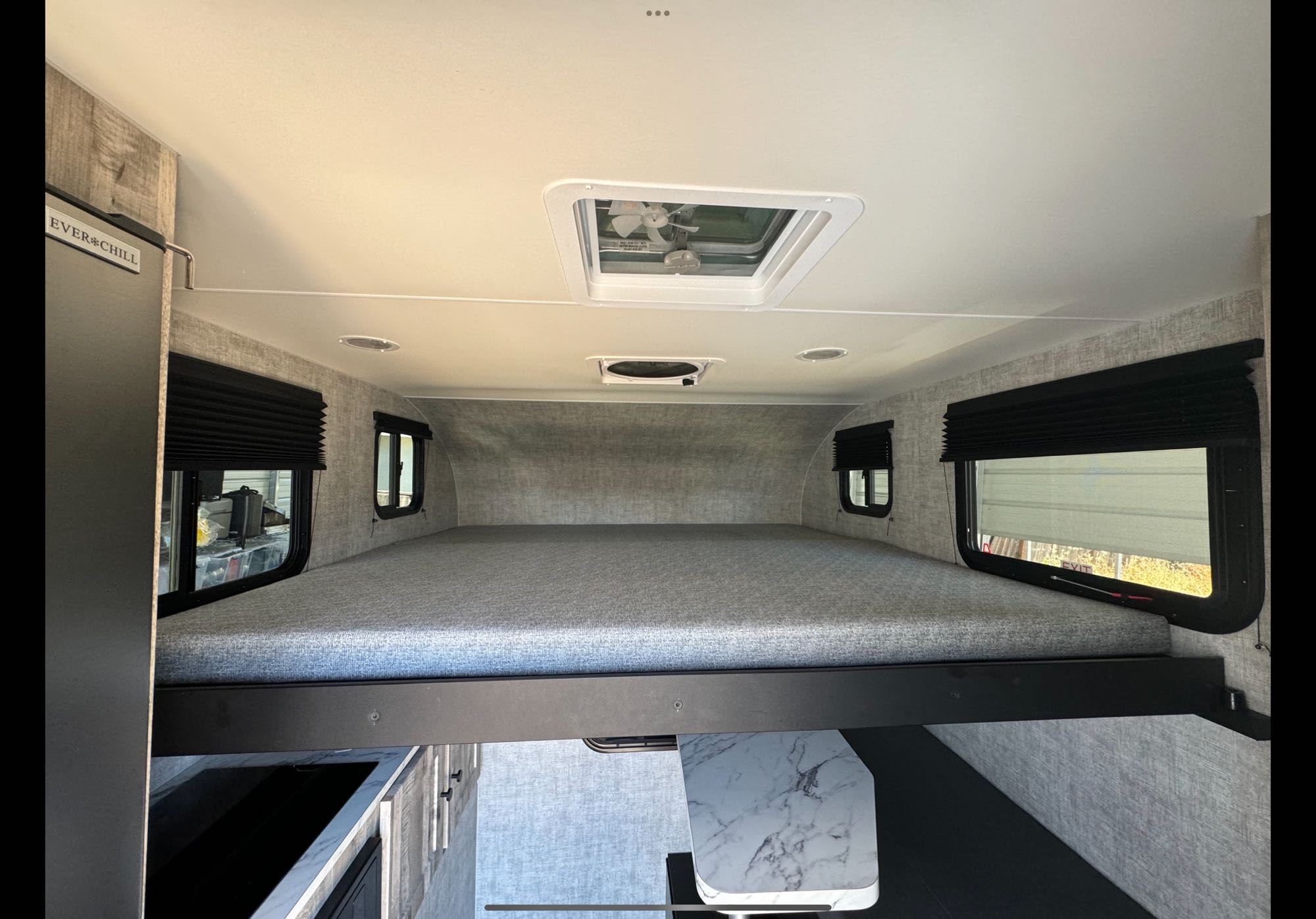 Inside a modern RV rental, featuring an elevated bunk bed, windows, kitchen counter, and "EVER*CHILL" fridge.. Ford Soaring eagle 2021