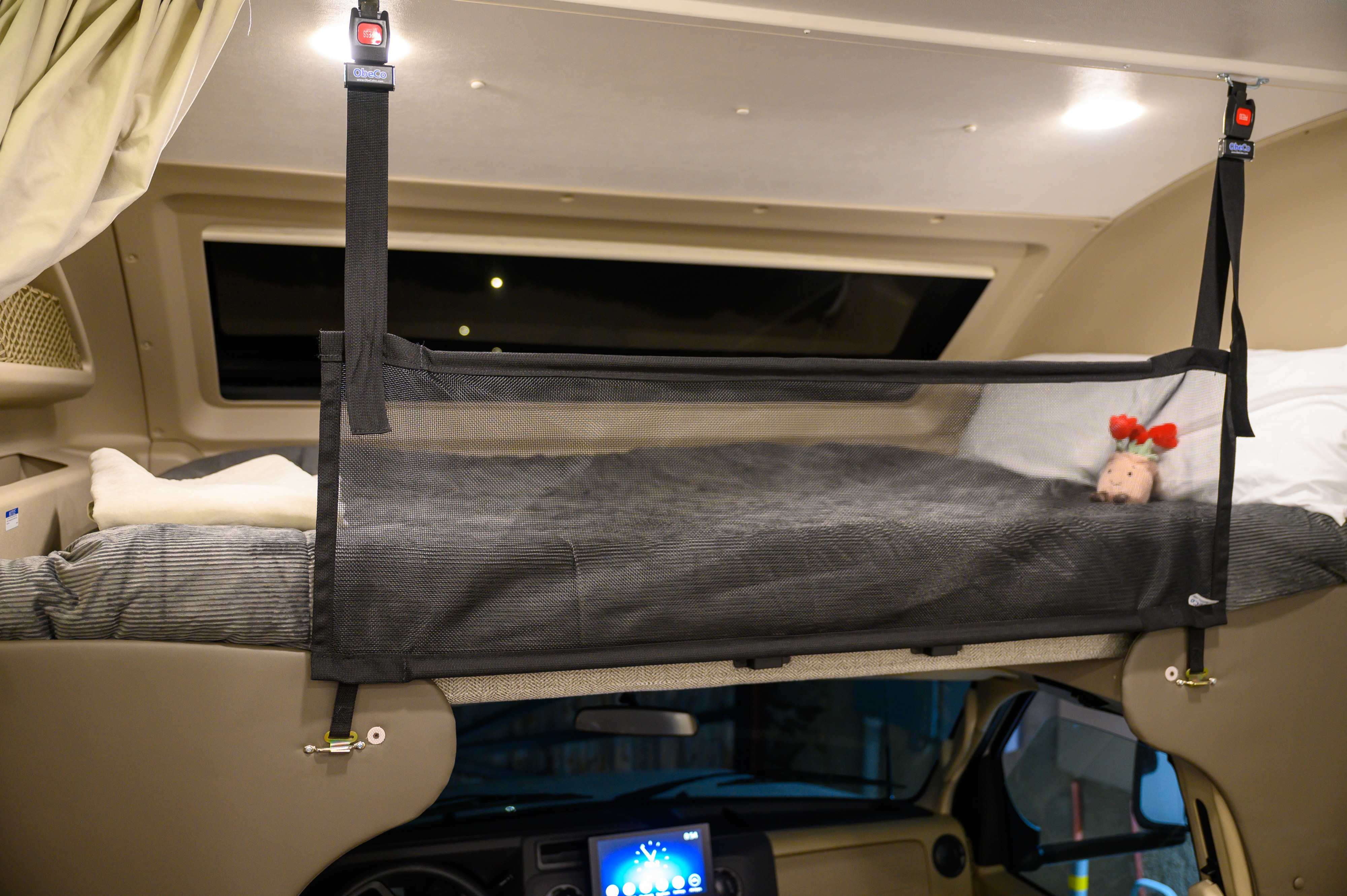 Long view inside a modern RV rental: light wood-look flooring leads to a sofa, dinette, kitchen, and driver's cockpit with an overhead bunk.. Entegra Odyssey 2025