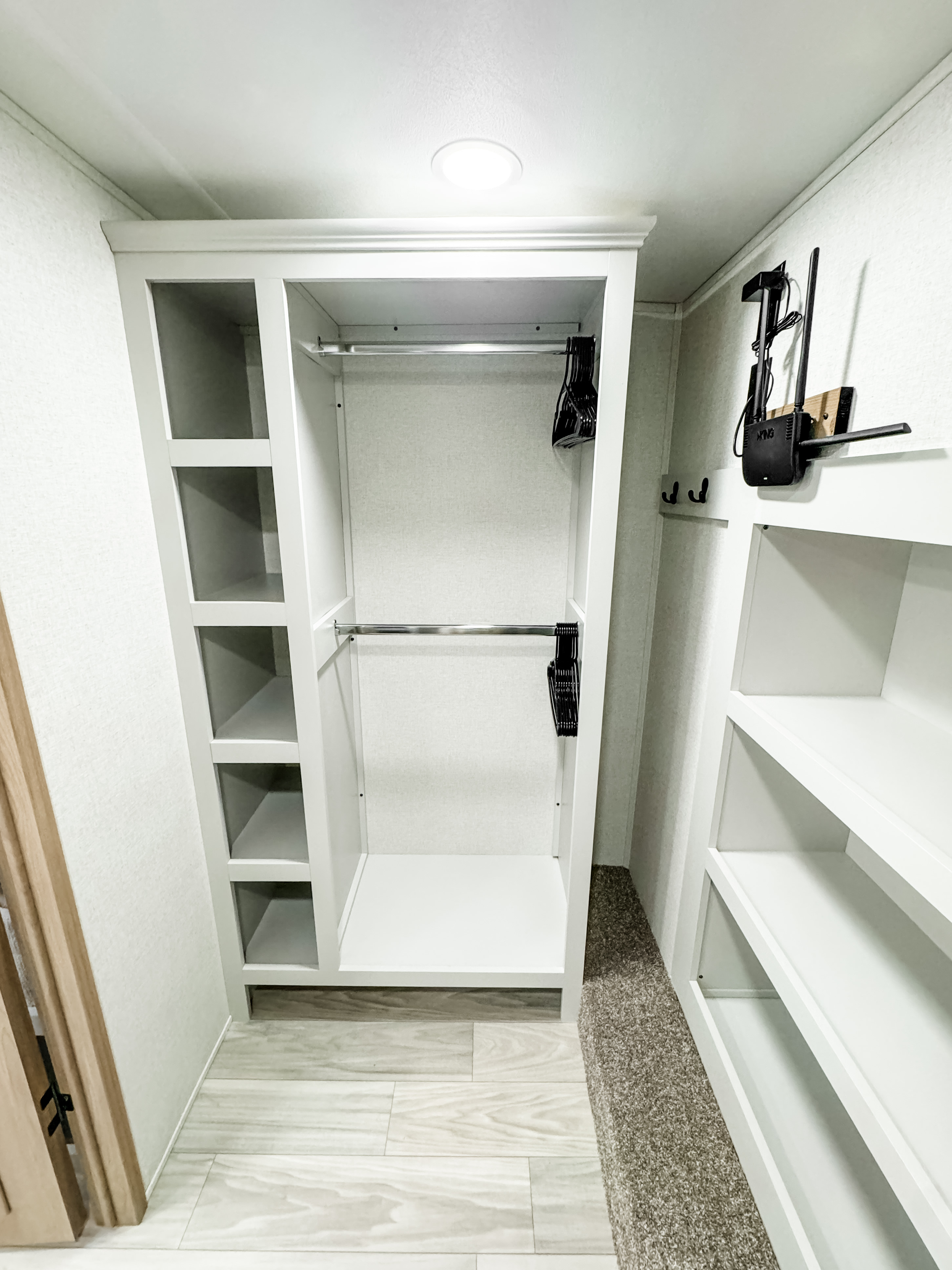 RV rental: Bright, empty built-in wardrobe with dual hanging rods, side shelves, and a wall-mounted router.. Forest River Sandpiper 2025
