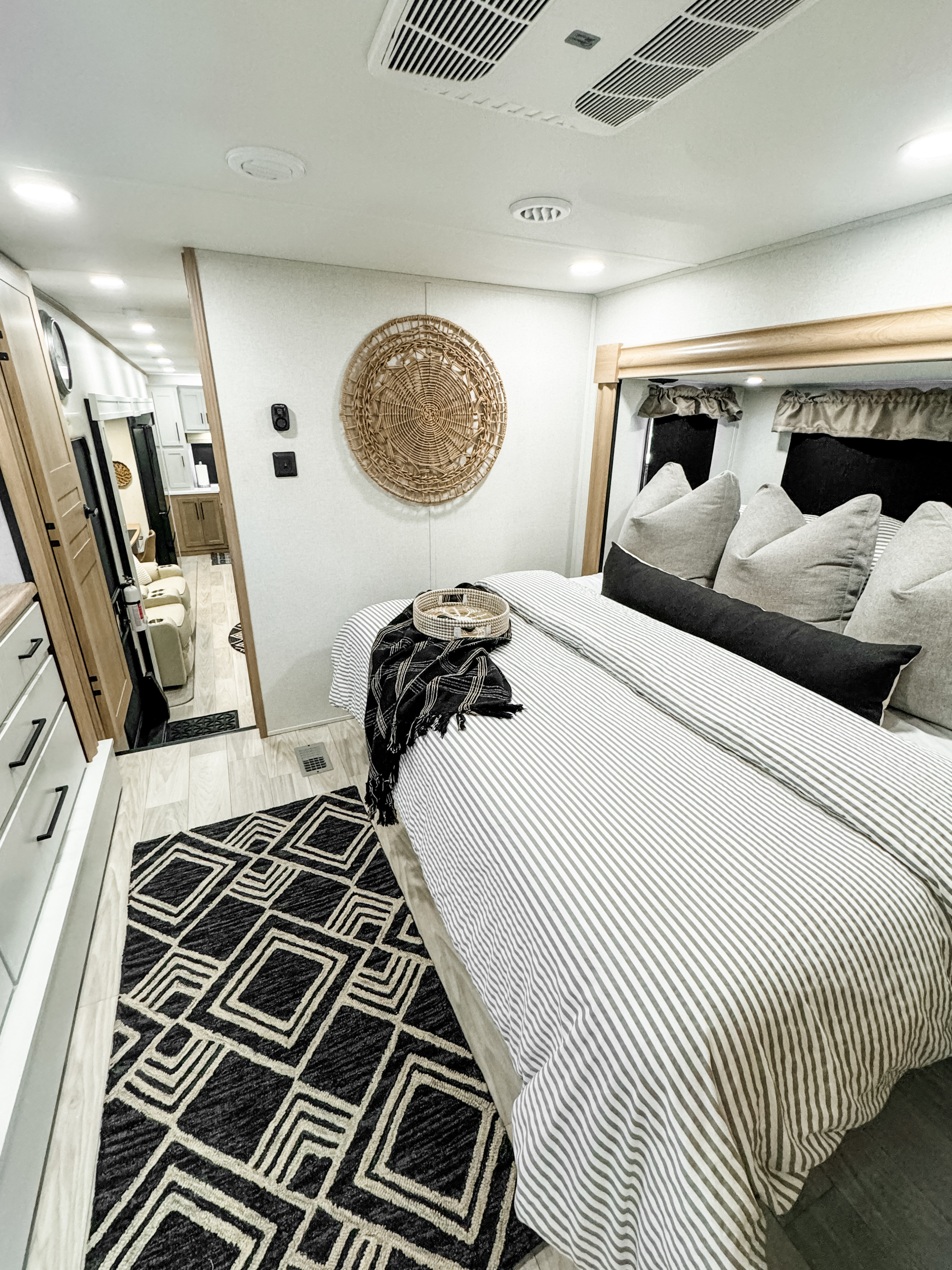 Modern RV rental bedroom with stylish striped bedding & geometric rug. A cozy, well-designed space for travel.. Forest River Sandpiper 2025