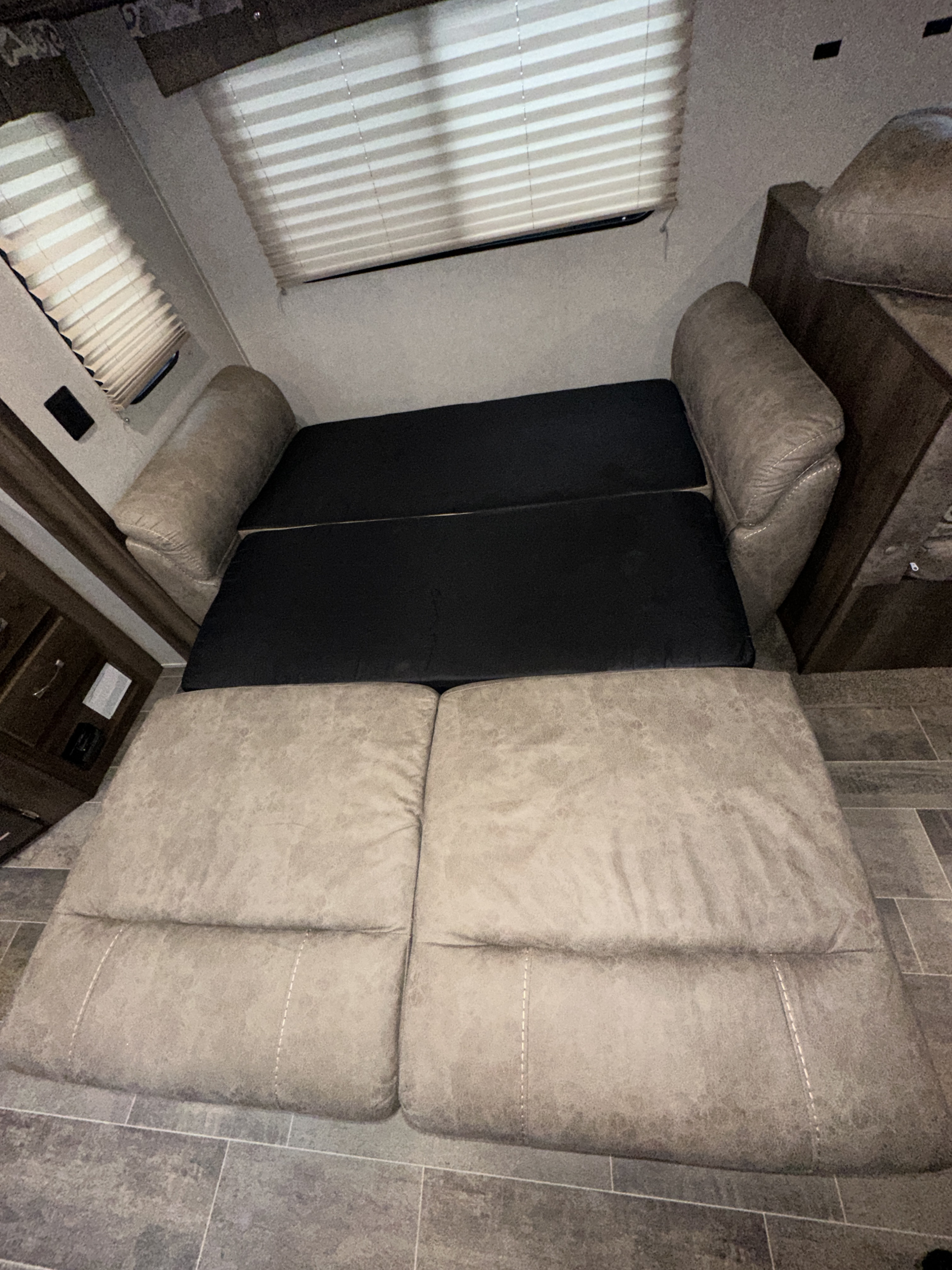 Inside an RV rental: a functional light gray sofa transforms into a bed, flanked by wood cabinetry.. Palomino Puma 2019