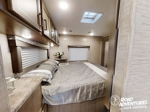 Cozy RV rental bedroom featuring a comfortable bed, overhead cabinets, and a skylight for natural light.. Thor Motor Coach Four Winds 2023
