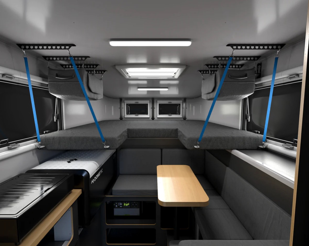 Modern RV rental interior: suspended bunks, dining, and compact kitchen. Ideal for comfortable adventure travel.. Adventurer 2015 Tacoma 2024