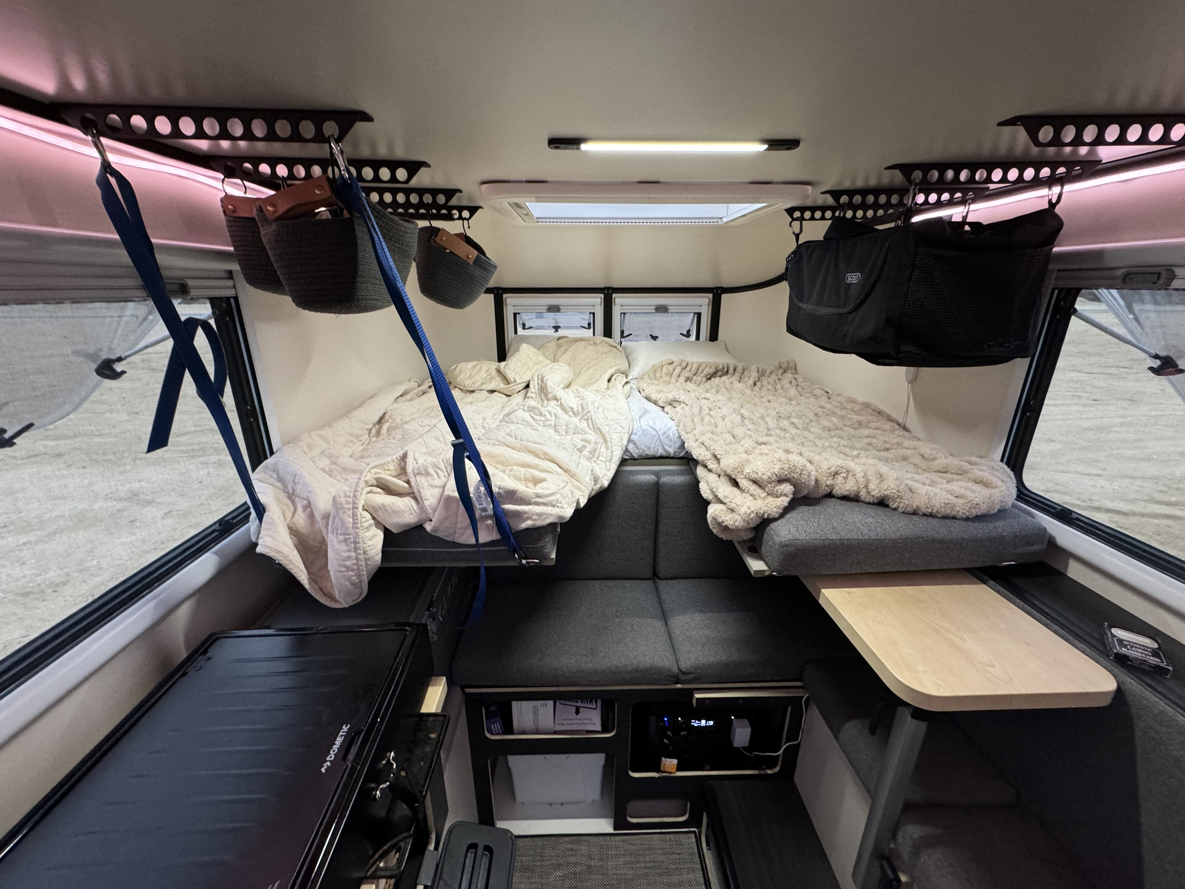 Cozy RV rental interior with two sleeping areas, overhead hanging storage, and a Dometic appliance.. Adventurer 2015 Tacoma 2024