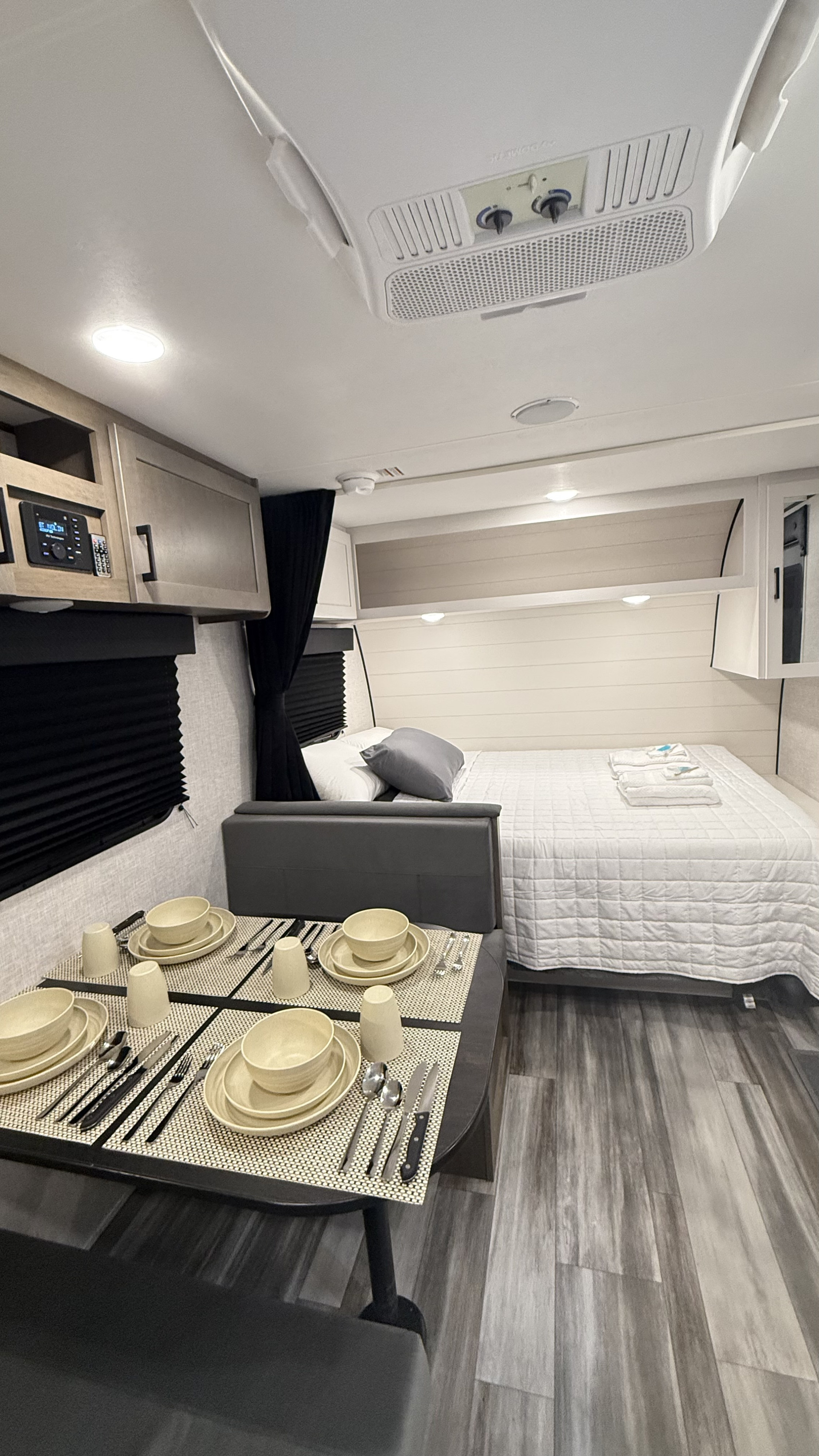 Inside a clean RV rental: compact dining table set for four next to a comfortable queen bed and shiplap wall.. Jayco Jay Flight SLX 175BH 2025