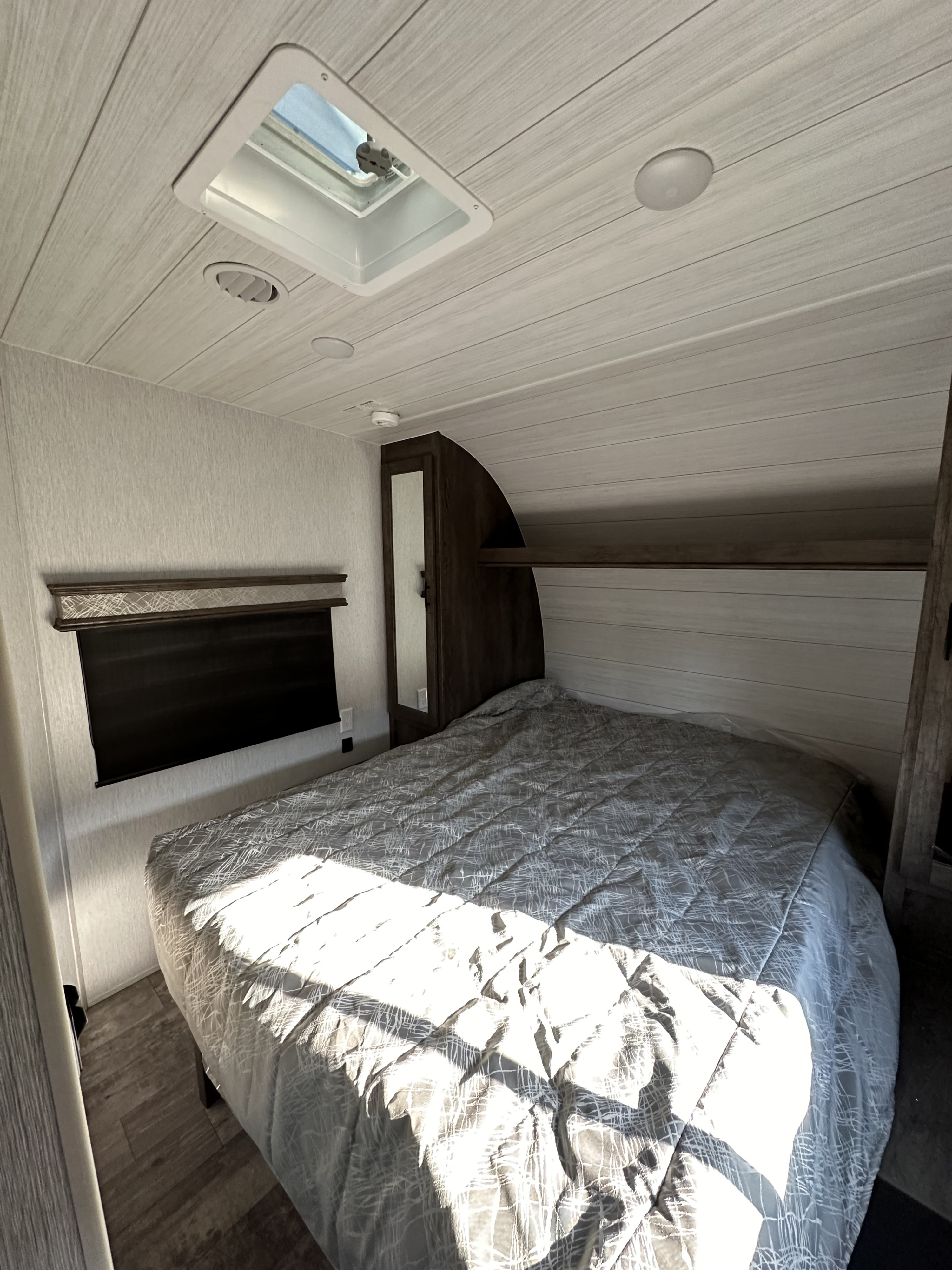 Spacious RV rental bedroom featuring a comfortable bed, modern light wood interior, and a ceiling vent.. Forest River Sandstorm 2022