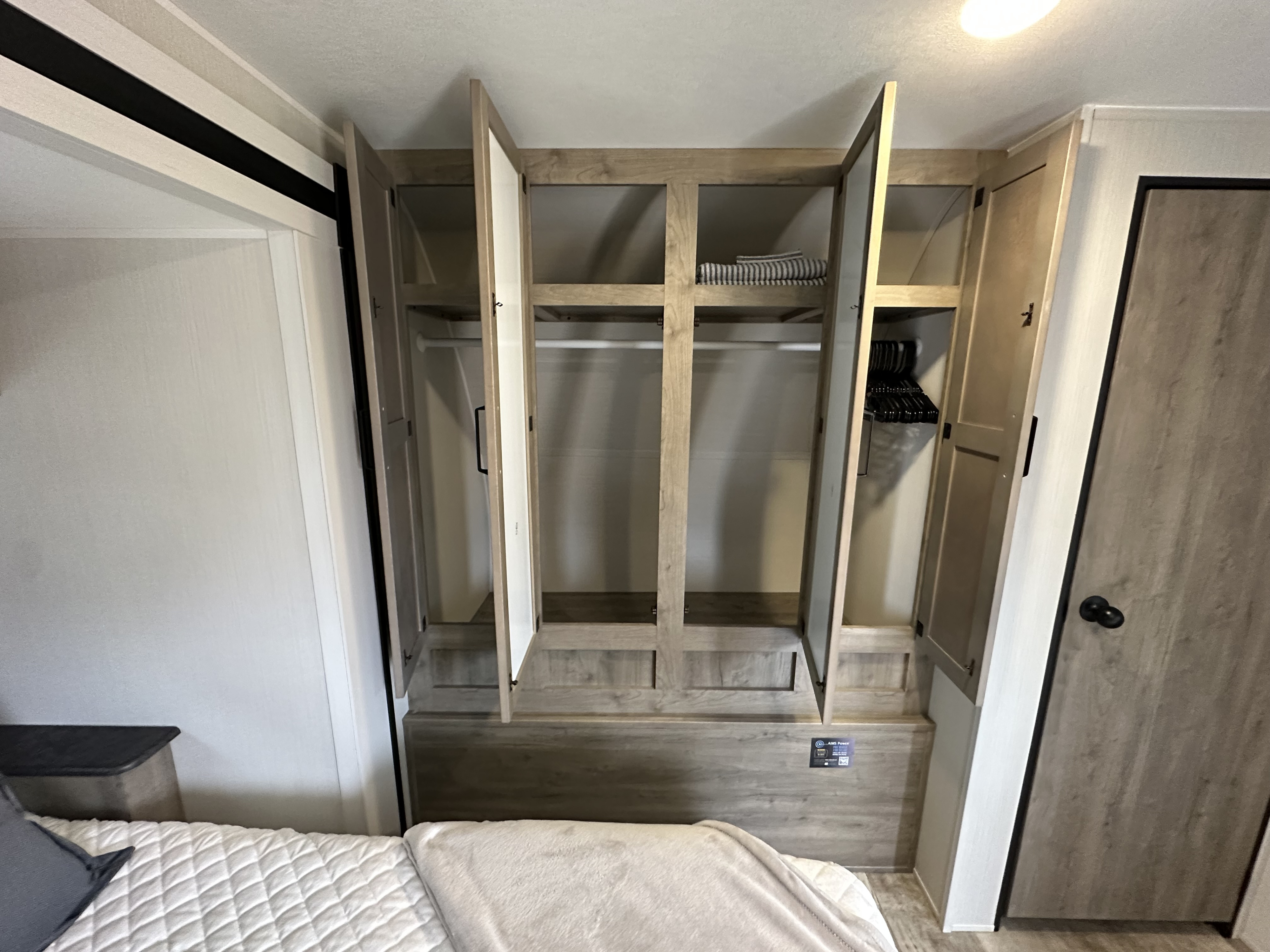 Spacious RV rental bedroom with ample built-in wardrobe storage, featuring hanging rods and shelves above the bed.. Palomino Puma 2024